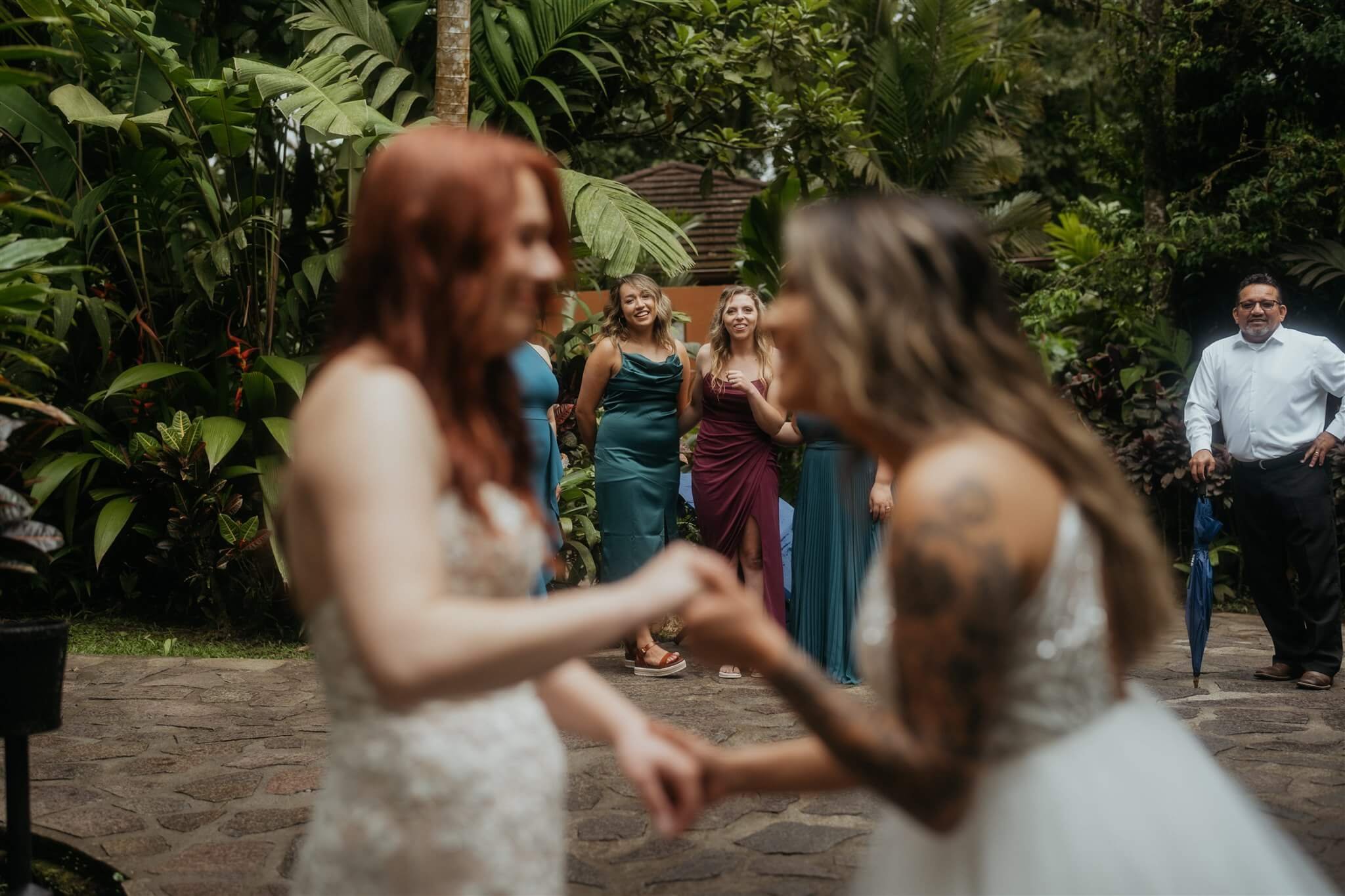 Two brides do first look while friends and family watch from afar