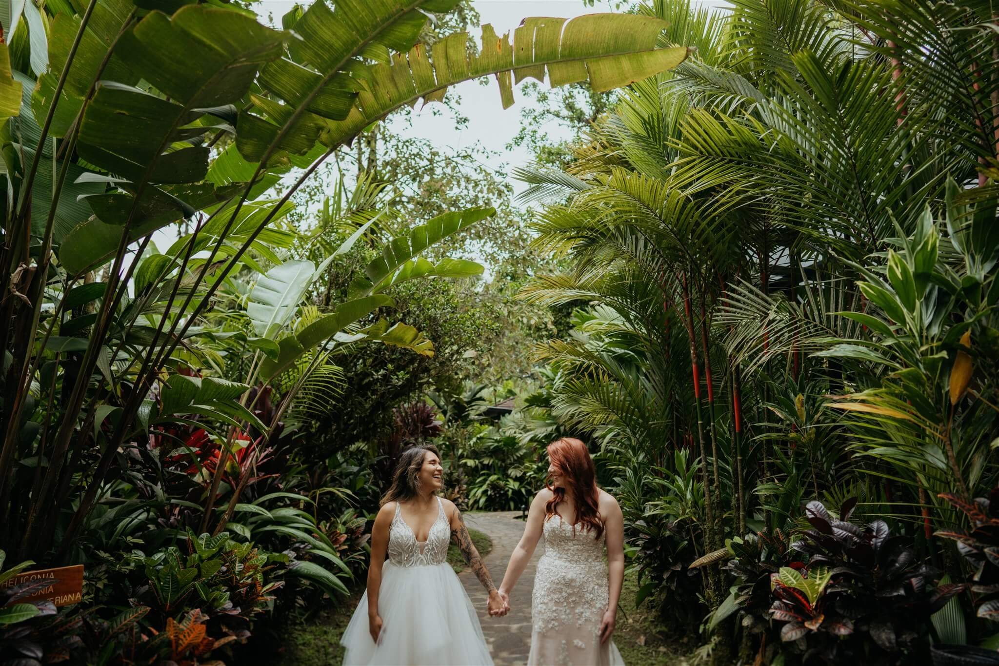 Two brides holding hands standing in the rainforest at Rio Celeste Hideaway