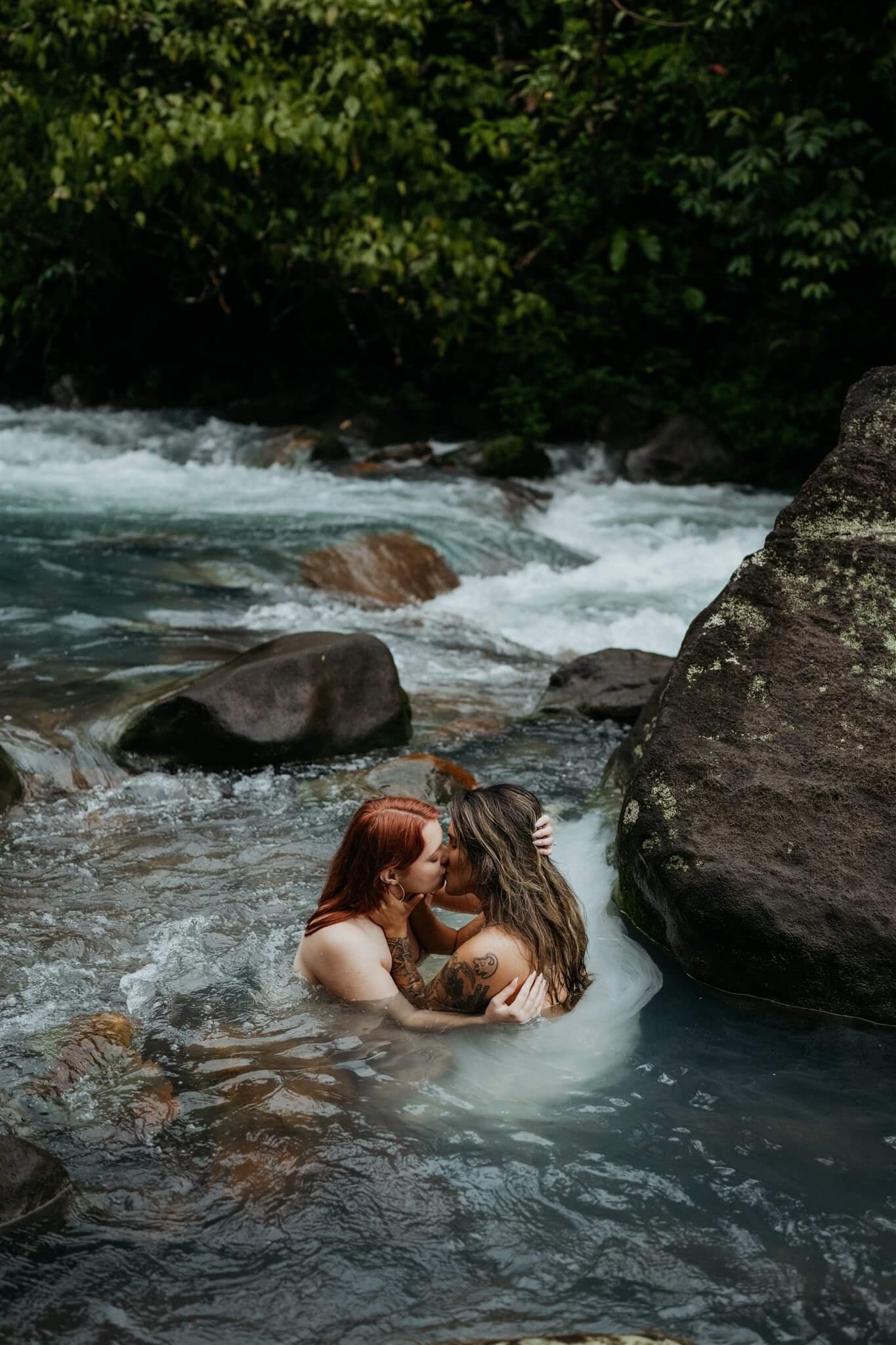 Two brides getting into the river during adventure elopement in Costa Rica