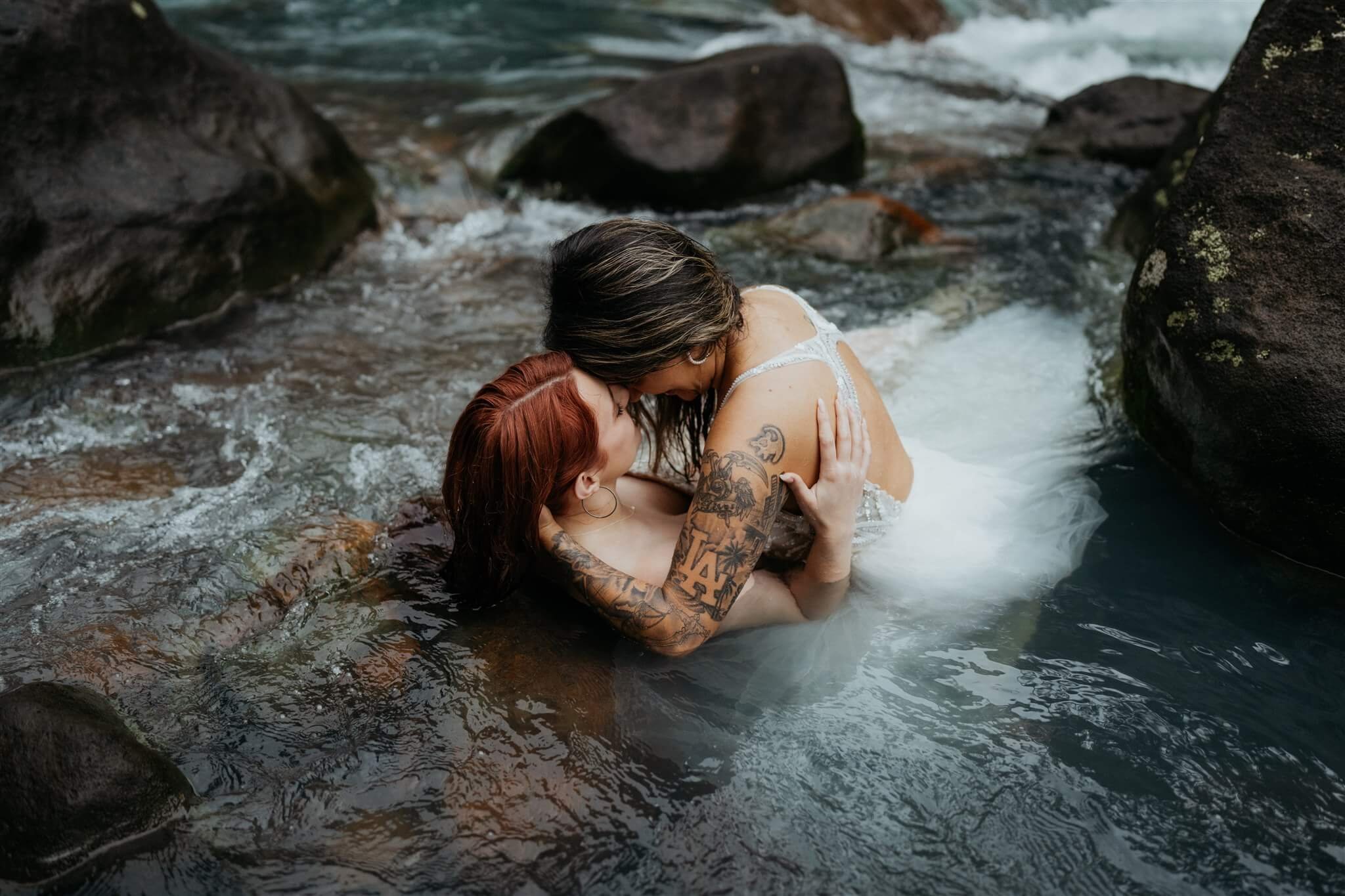 Two brides kissing in the river for adventure elopement photos