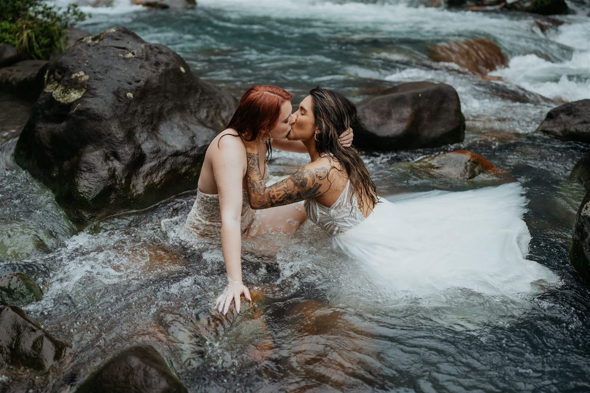 Two brides kissing in the river for adventure elopement photos