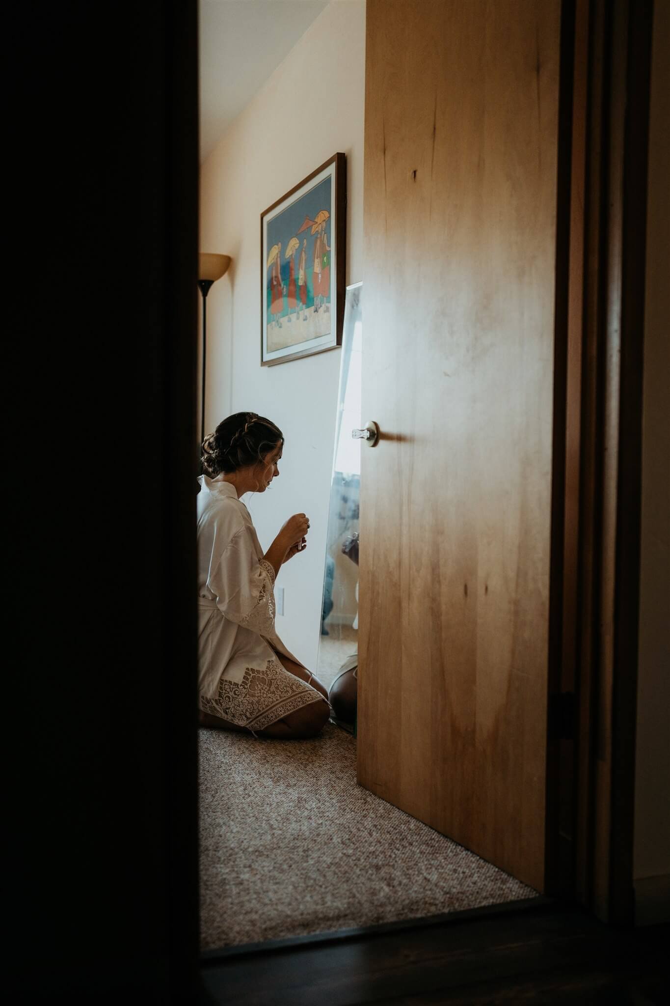 Bride kneeling in front of mirror applying makeup 