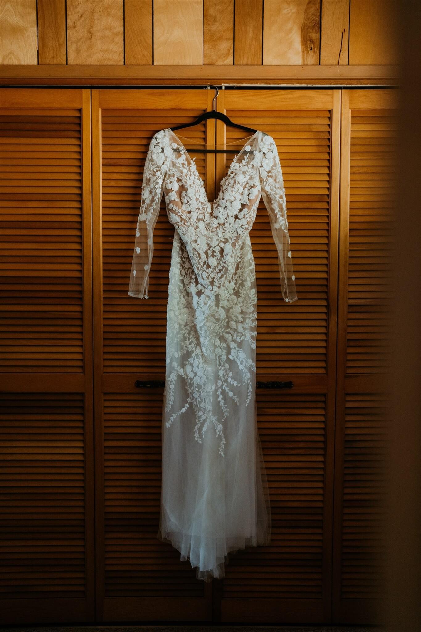 White lace wedding dress hanging on black hangar