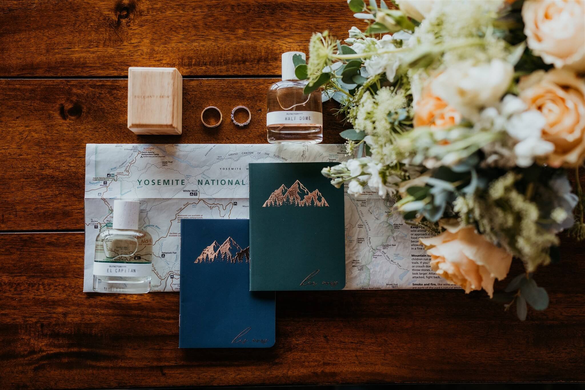 Yosemite elopement details with orange, white, and green floral arrangement and gold etched vow books