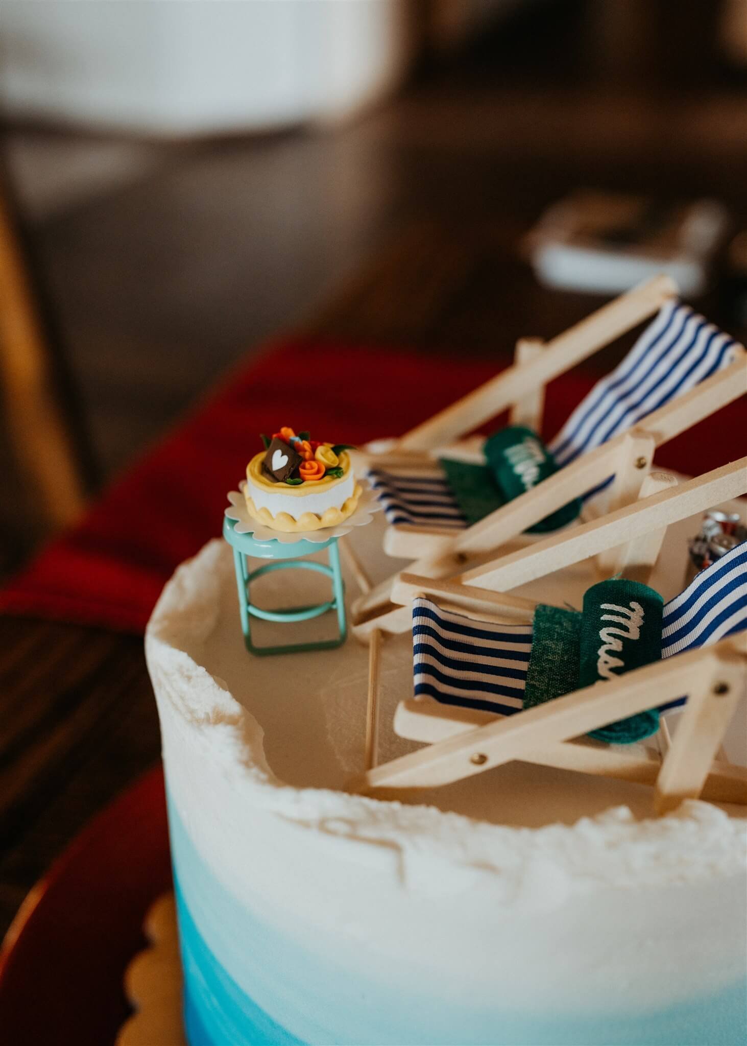 White and blue wedding cake with mini striped beach chairs and Mr. and Mrs. embroidered pillows
