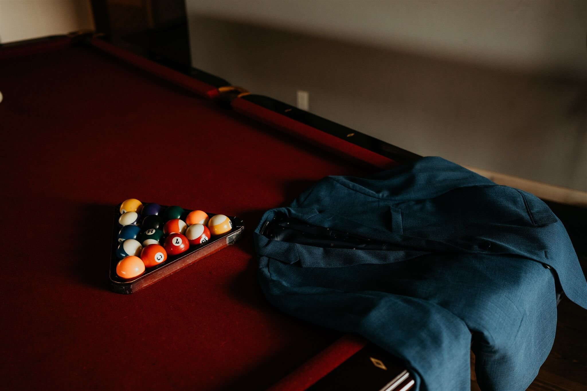 Navy blue groom suit laying on red pool table