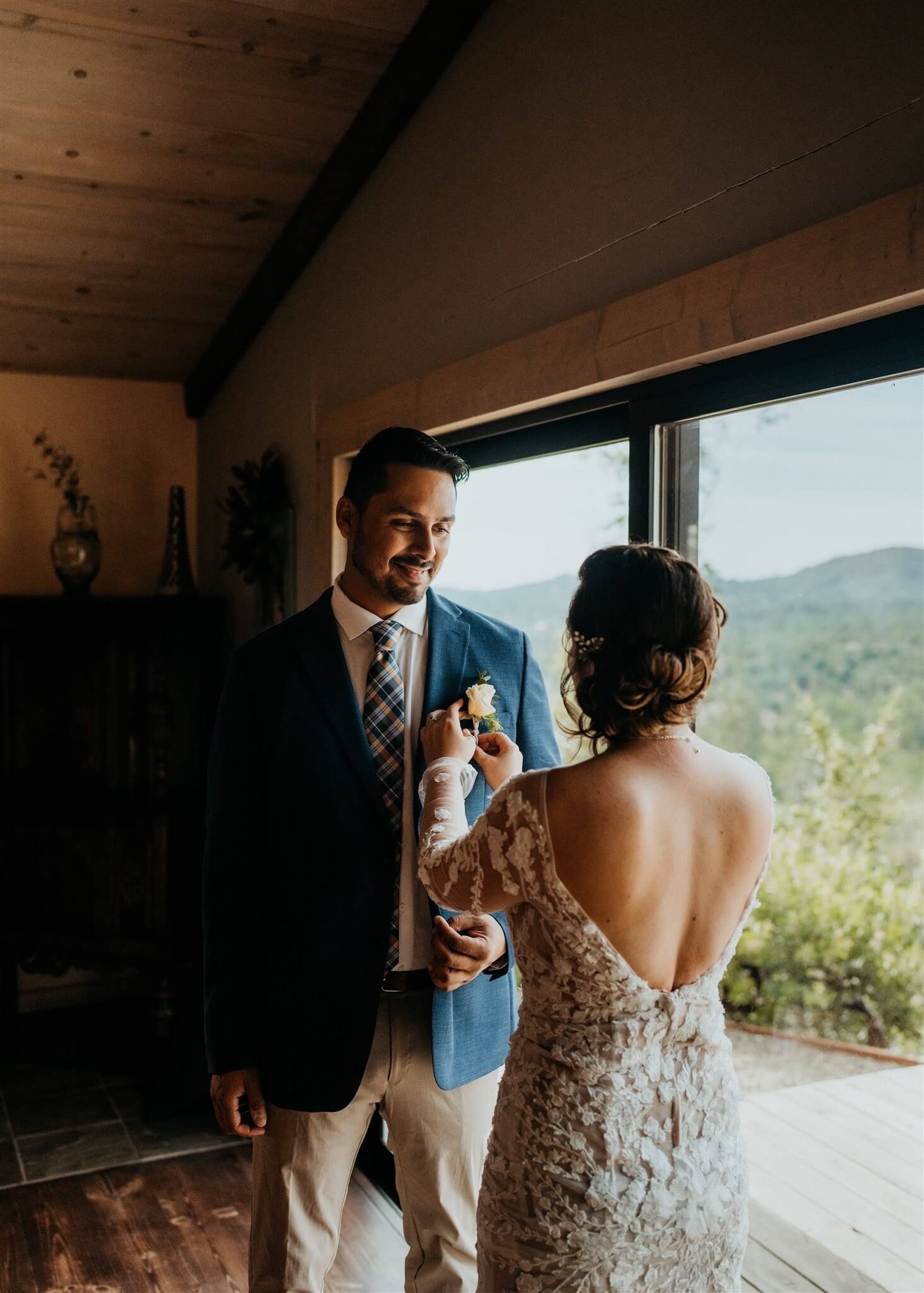 Bride adjusts boutonniere on groom's navy blue suit