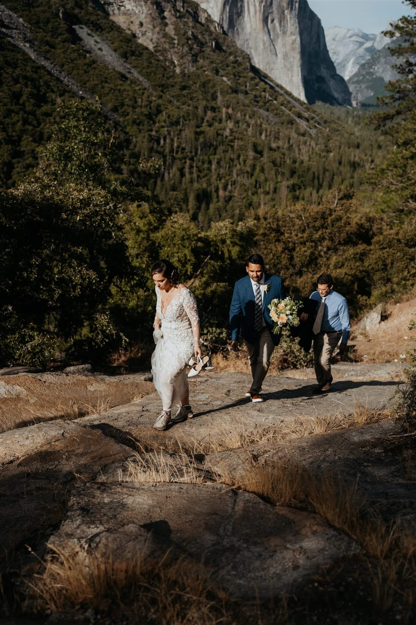 Bride, groom and officiant hiking up the hill at Tunnel View for elopement in Yosemite