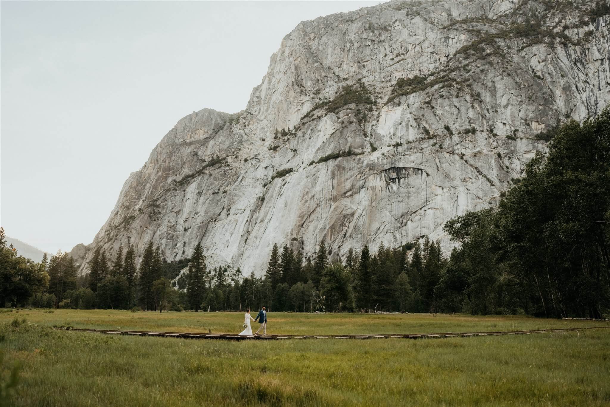 Bride and groom walk across the field during national park elopement in Yosemite