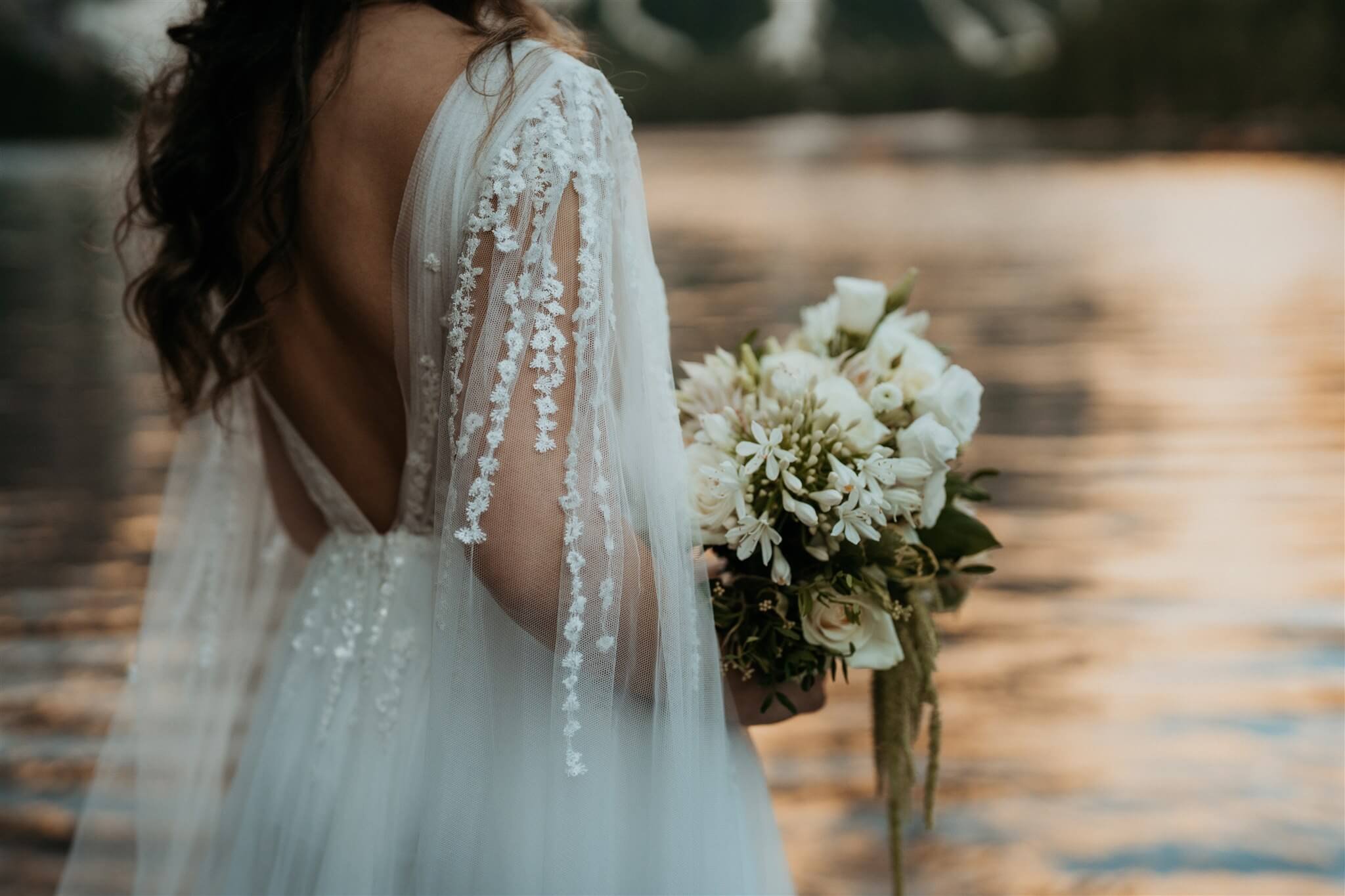 Bride wearing backless lace wedding dress with cape sleeves