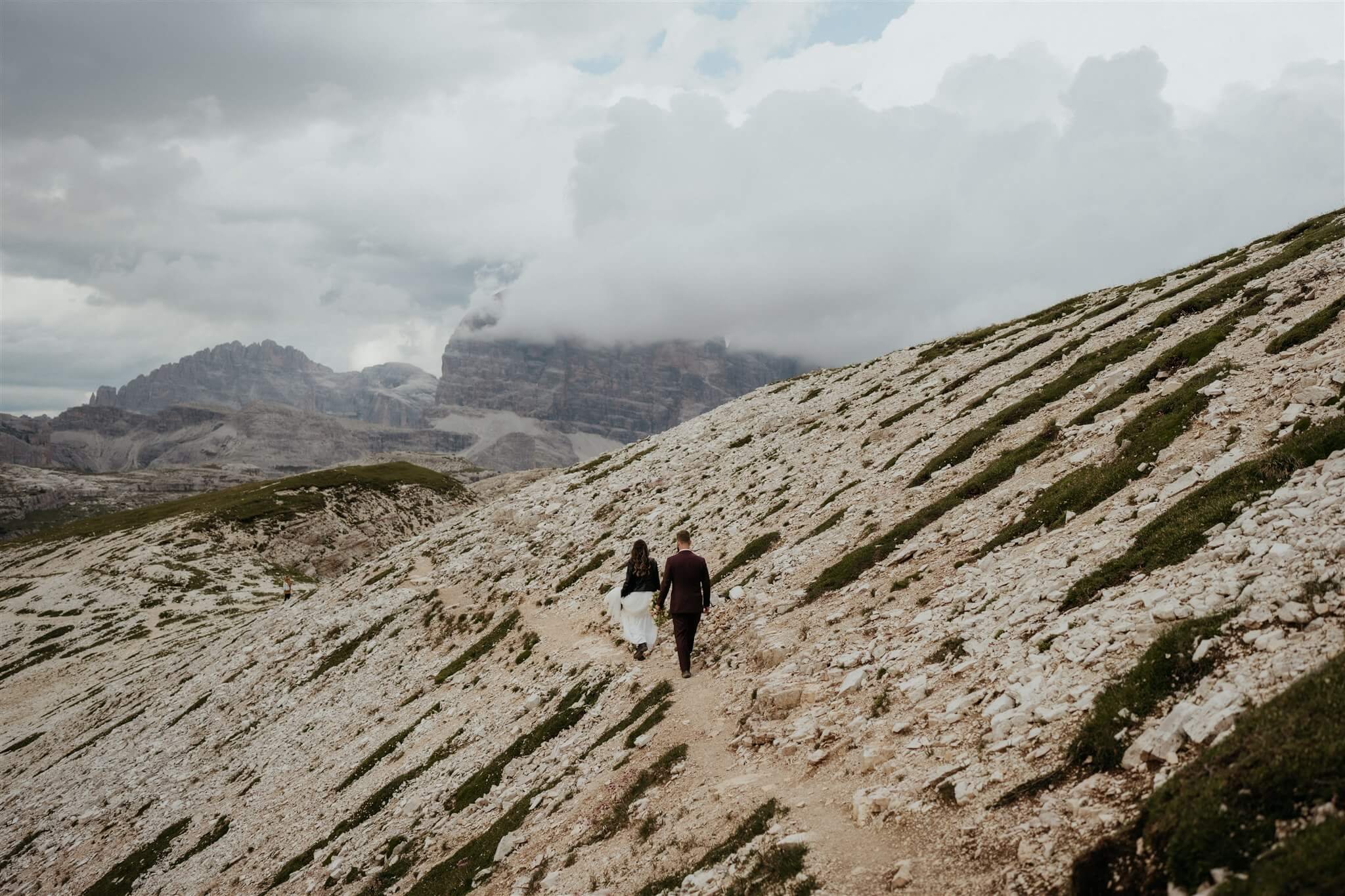Bride and groom hiking back after vow renewal elopement in the Dolomites