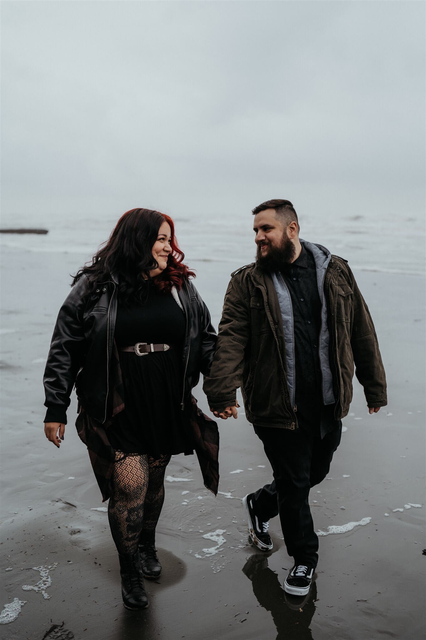 Couple holding hands walking along Ruby Beach for Halloween engagement session