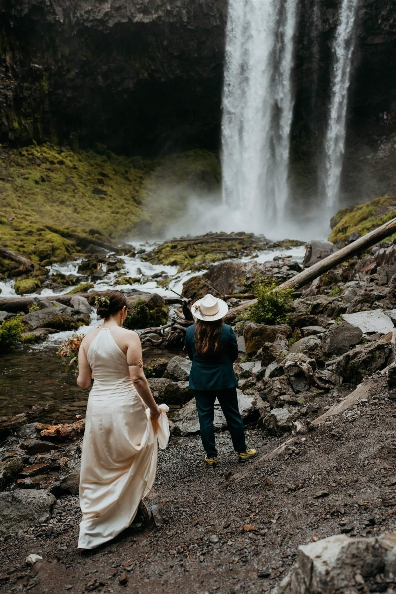 Two brides first look in front of a waterfall before Mt Hood elopement