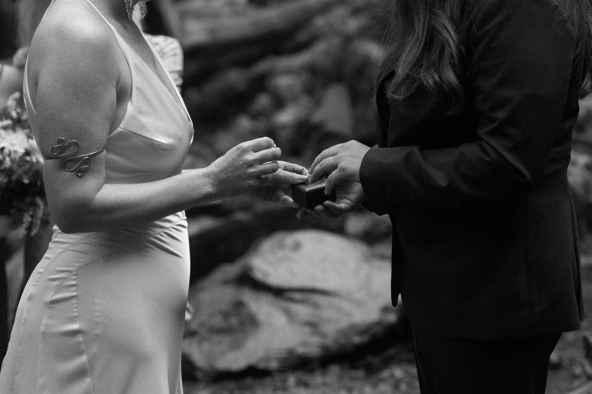 Brides exchange rings at waterfall elopement in Mt Hood