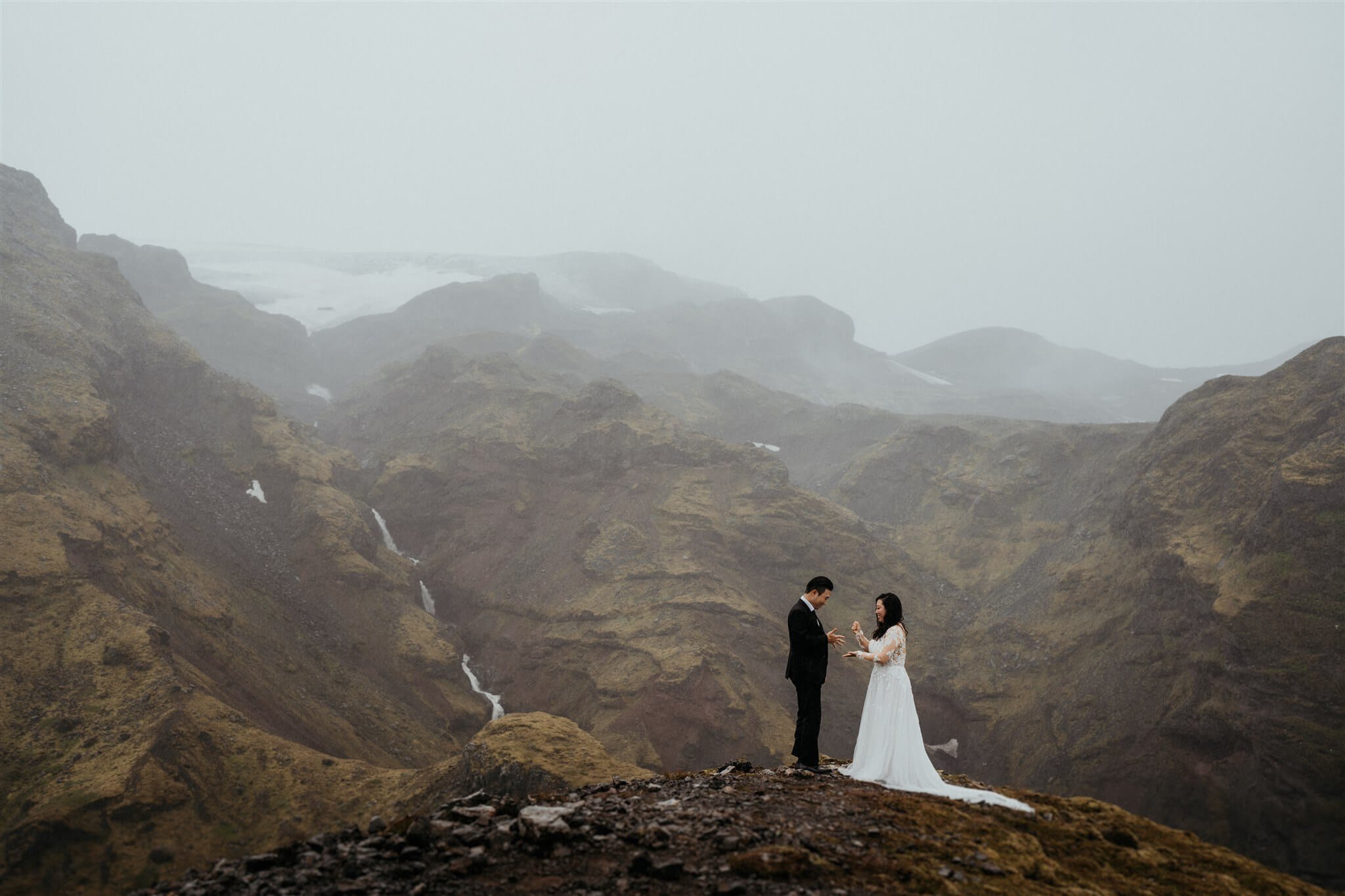 Bride and groom elopement in Iceland overlooking a waterfall in the canyon