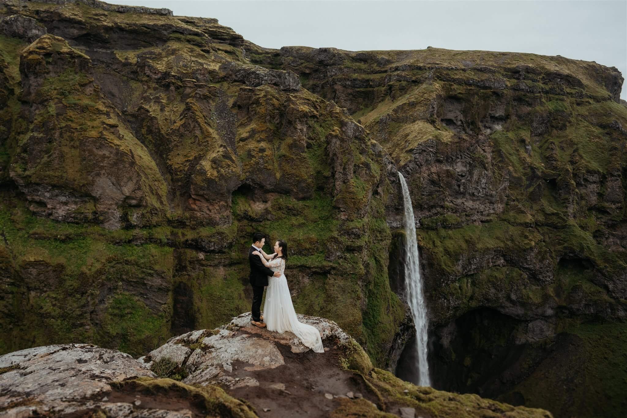 Bride and groom kiss in front of a waterfall during elopement in Iceland