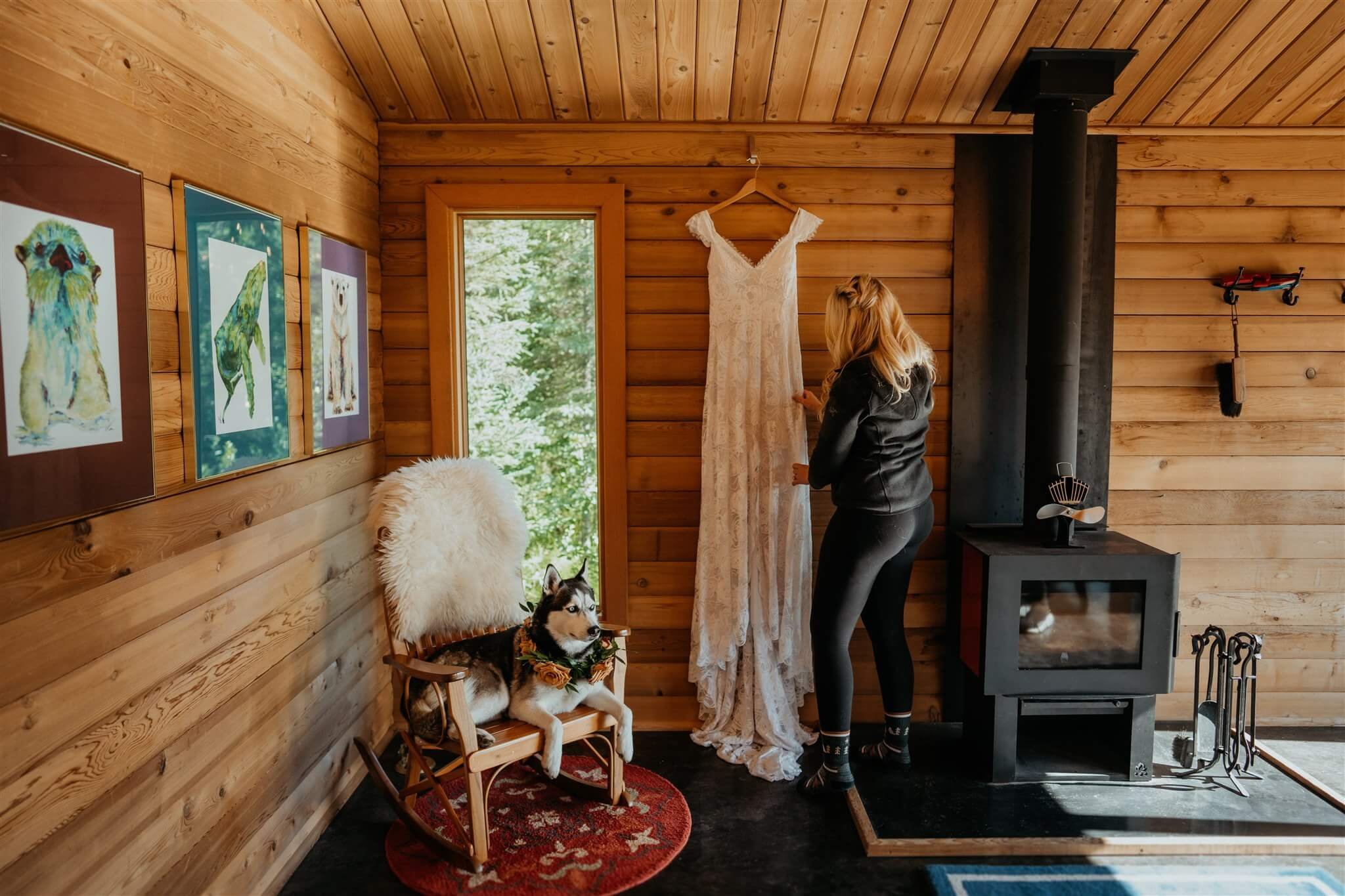 Bride smoothing white wedding dress while black and white husky lays beside her on a rocking chair