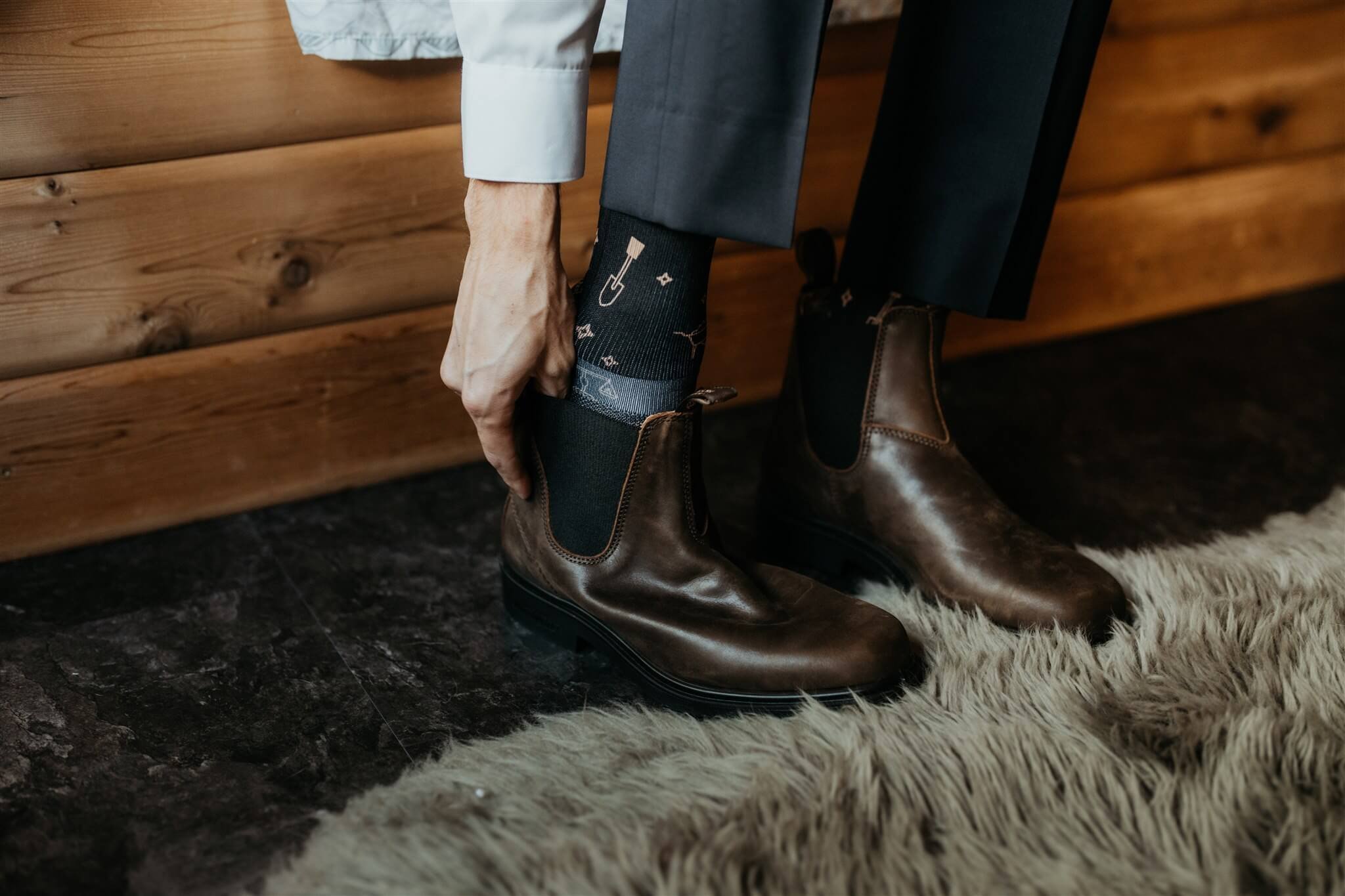 Groom putting on brown leather boots for adventure elopement in Alaska