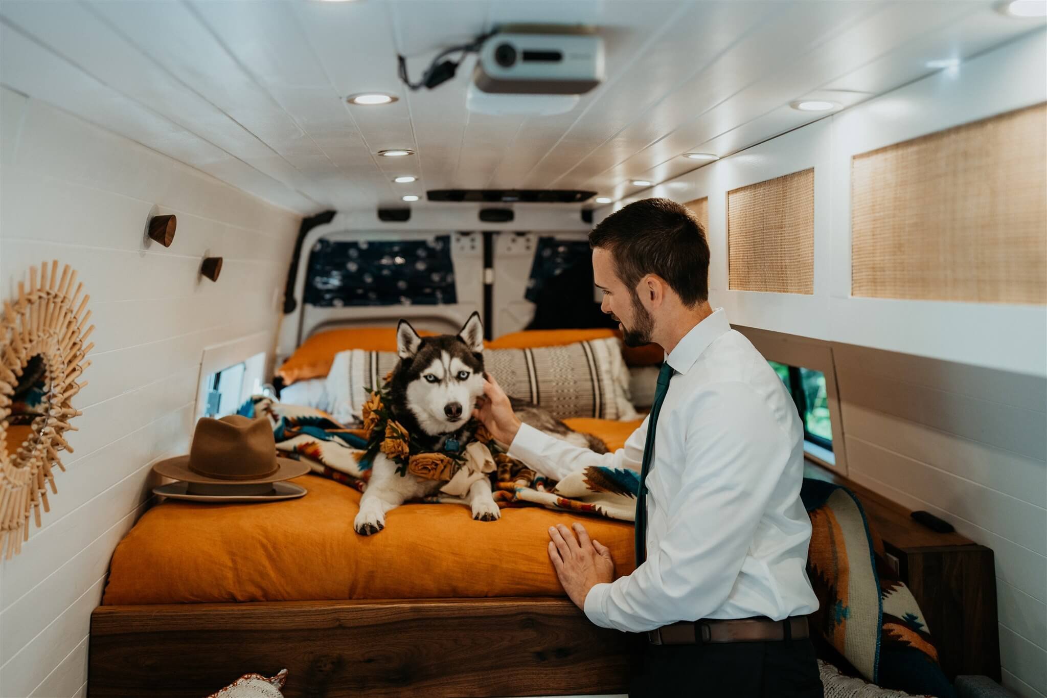 Groom and husky sitting in the camper van before helicopter elopement