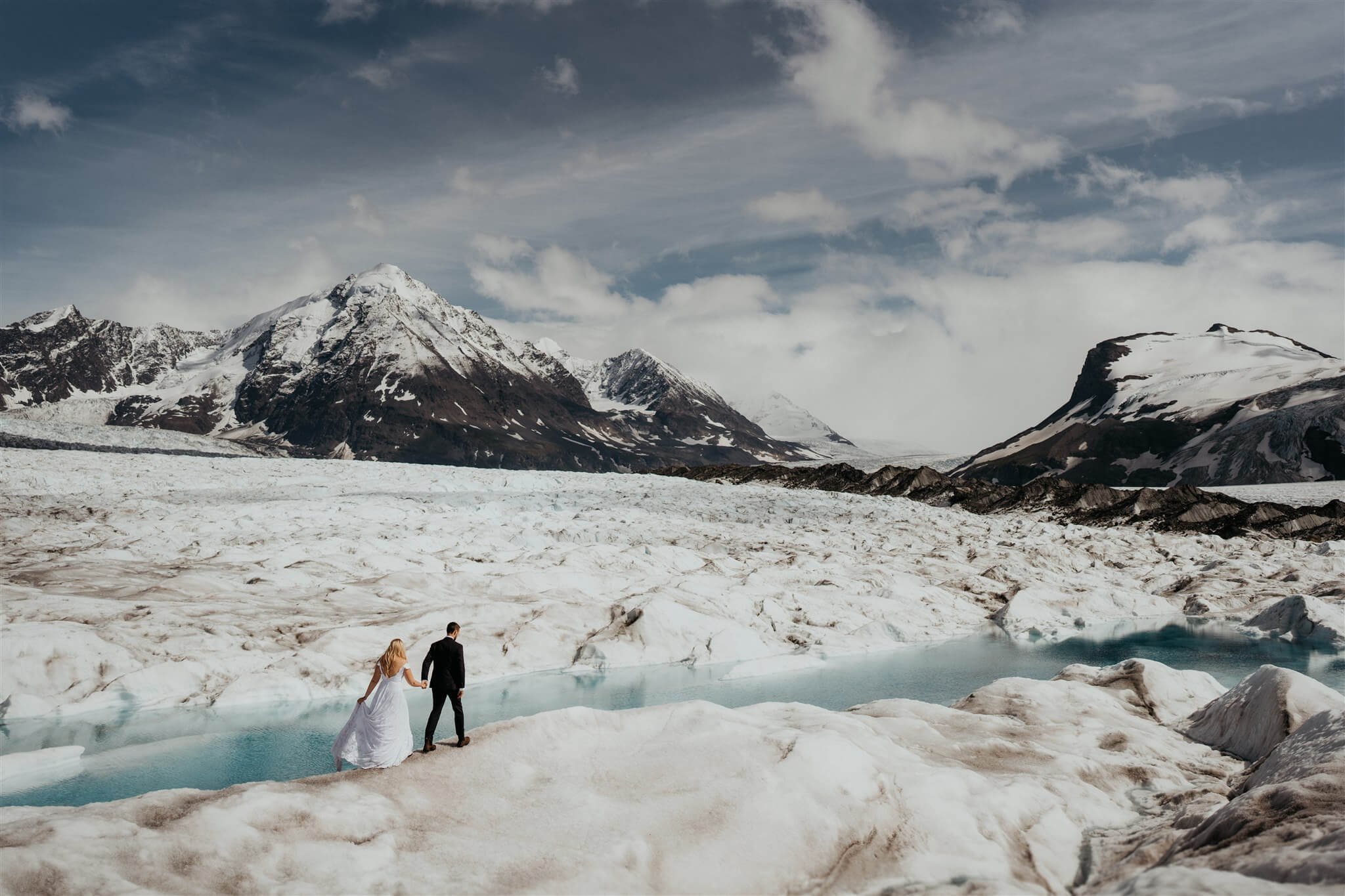 Bride and groom walking toward their ceremony location on a glacier in Alaska