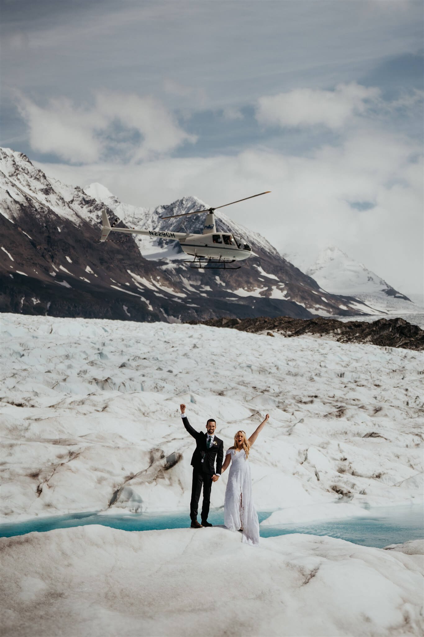 Bride and groom celebrate during helicopter elopement on an Alaskan glacier