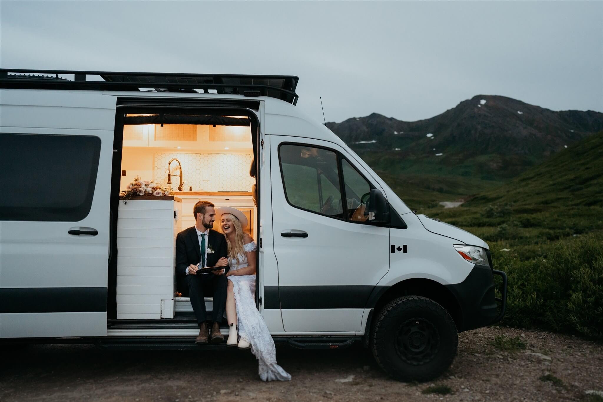 Bride and groom sign marriage license in their camper van after Alaska helicopter elopement