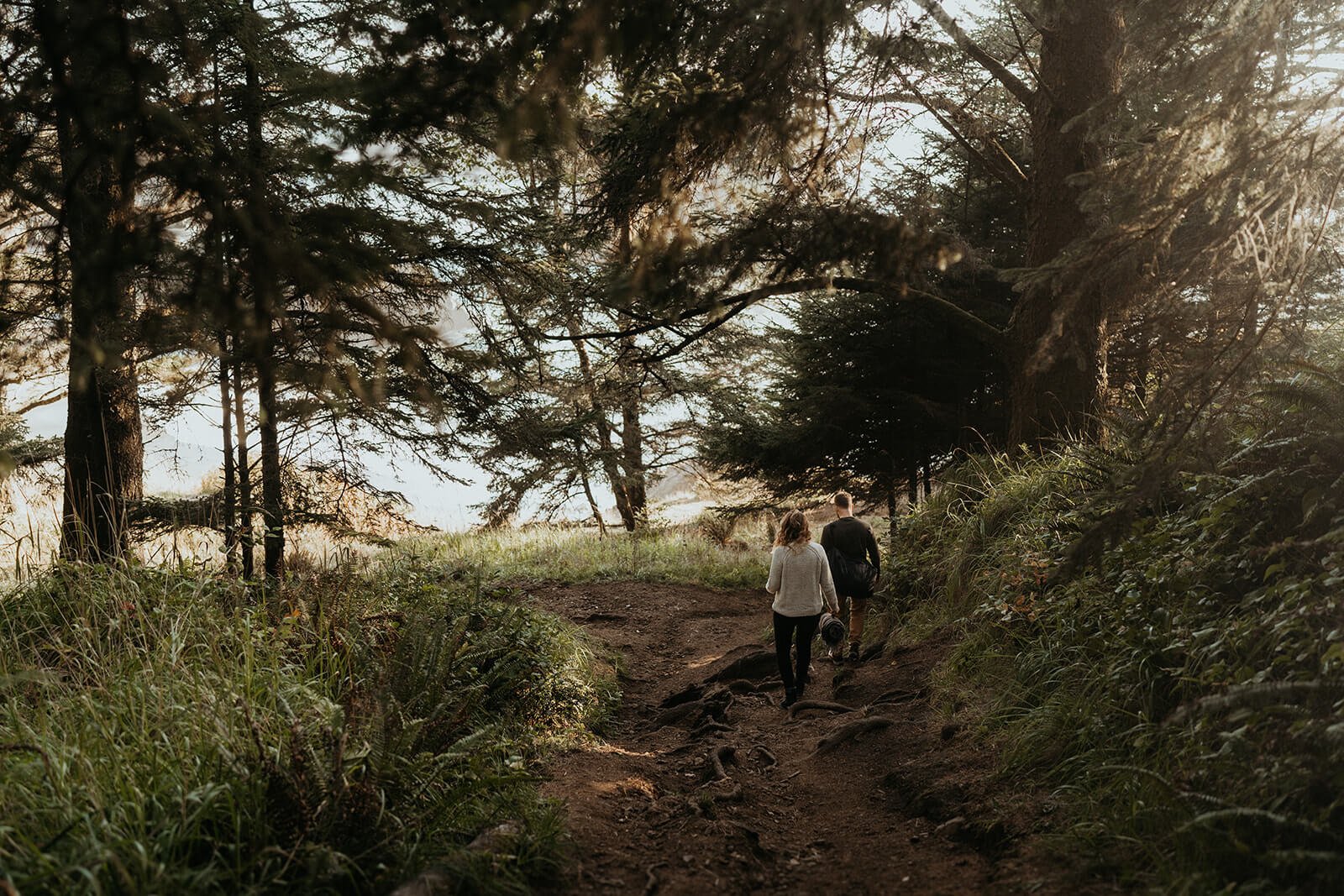 Man and woman hiking down a trail for their couple photo shoot on the Oregon Coast
