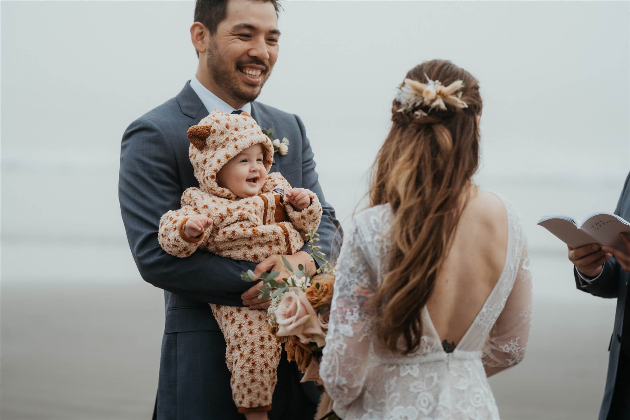 Groom holding baby during La Push Beach elopement