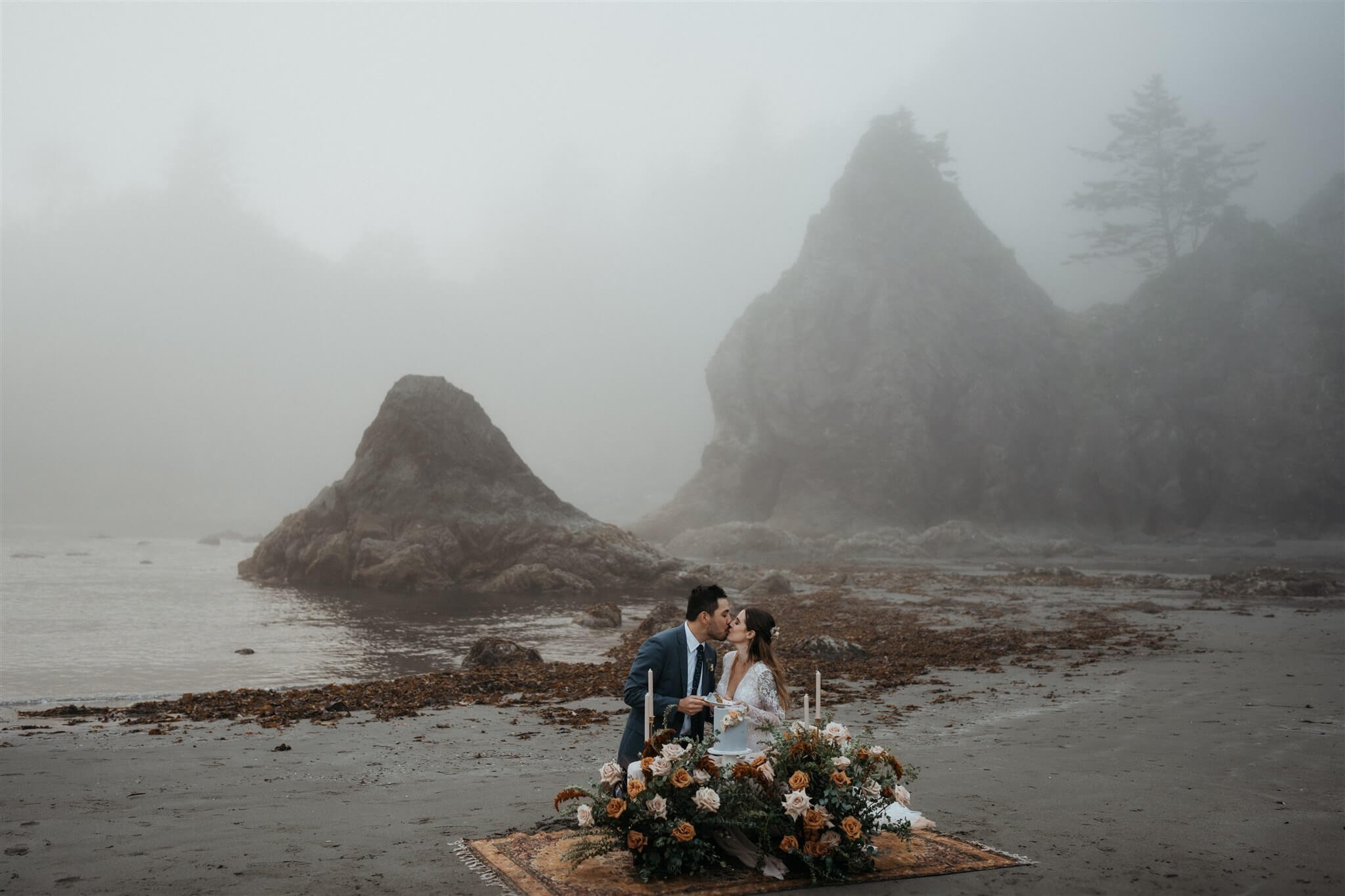 Bride and groom kiss at their sweetheart table on La Push Beach