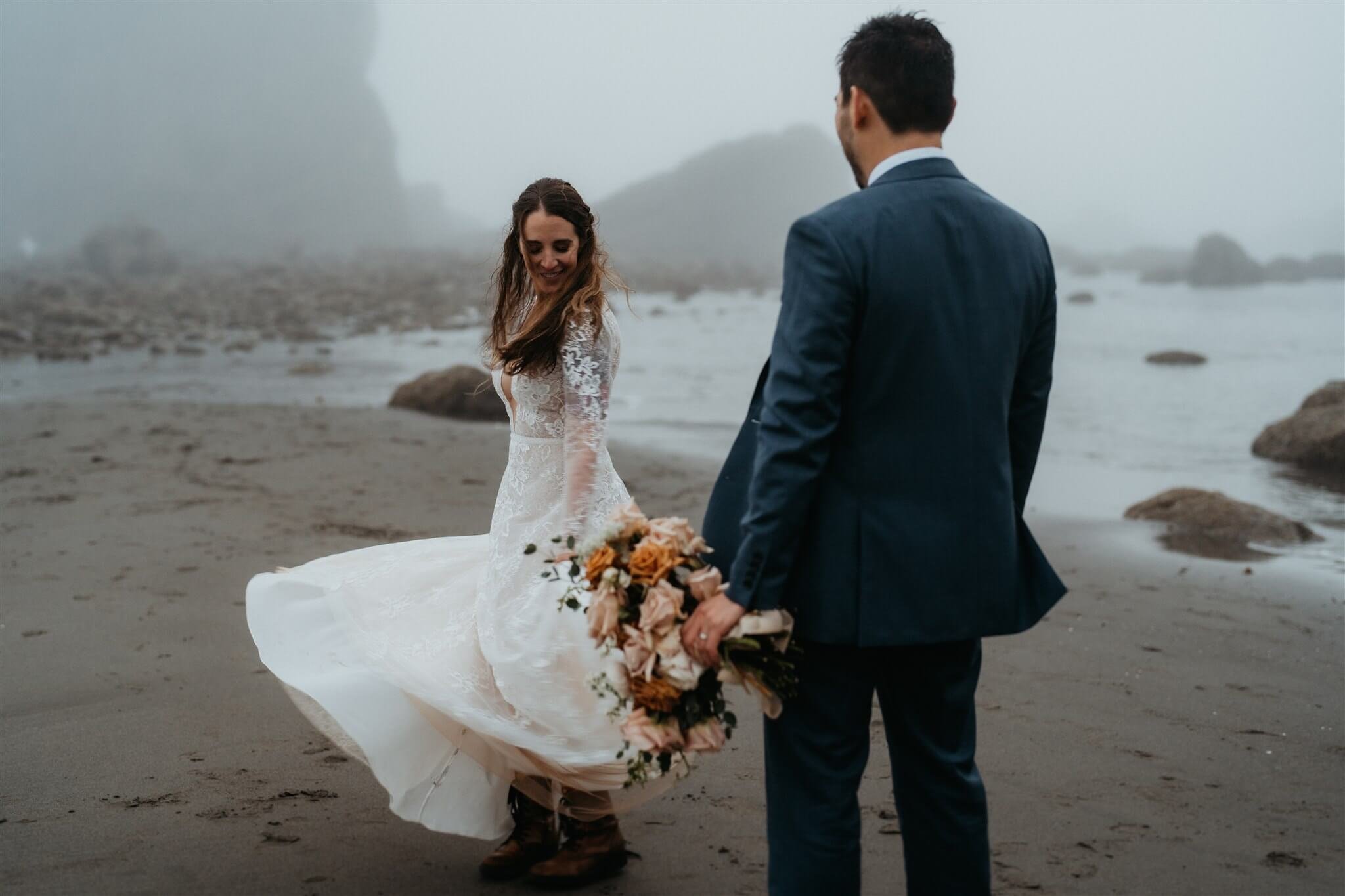 Bride dancing on the beach in the rain after eloping with family