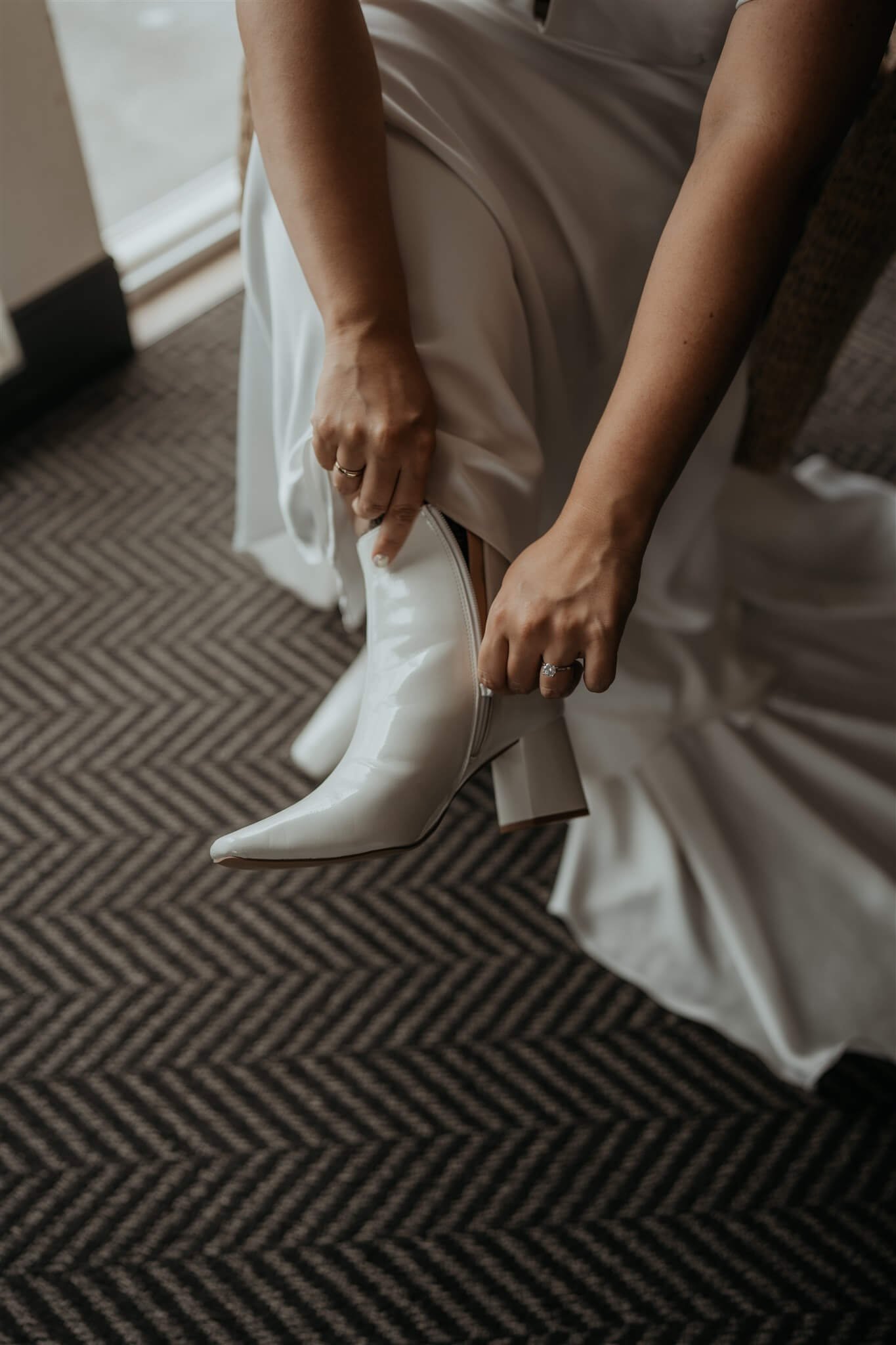 bride lacing up white leather boots for flower filled wedding