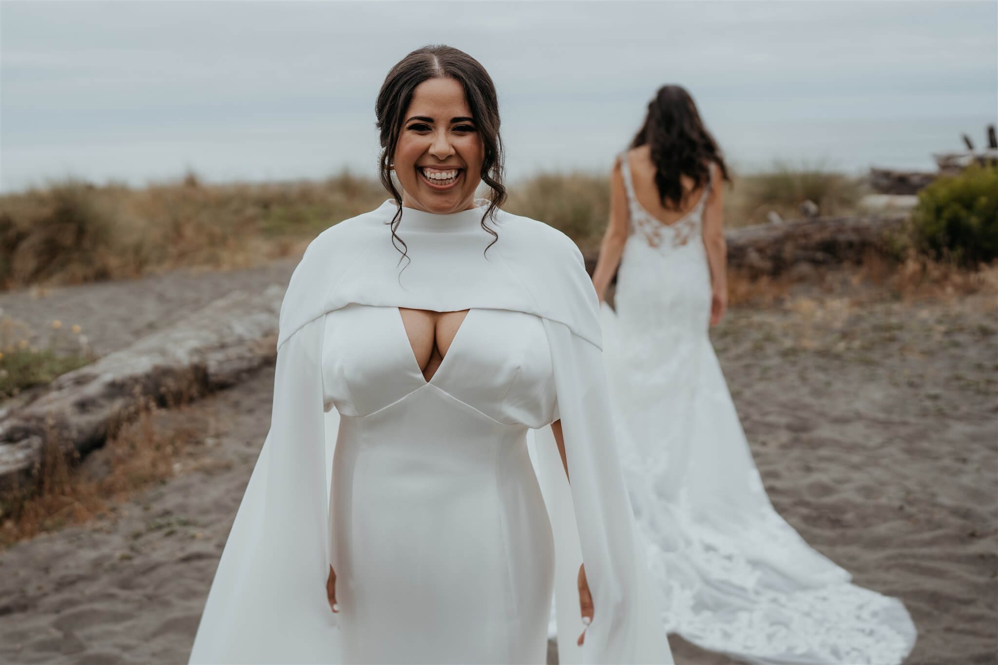 two brides waiting to do first look on the beach at flower filled wedding