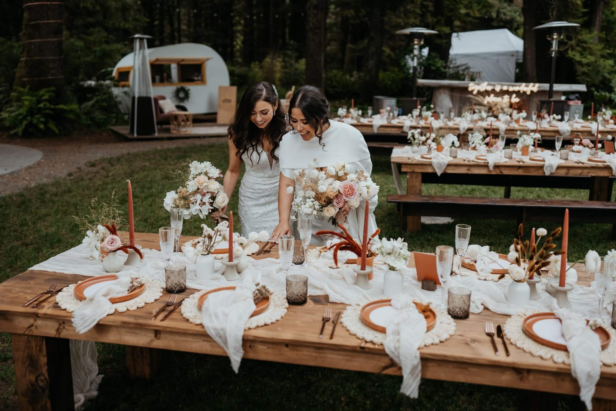 Brides looking at wedding reception table decor at flower filled wedding