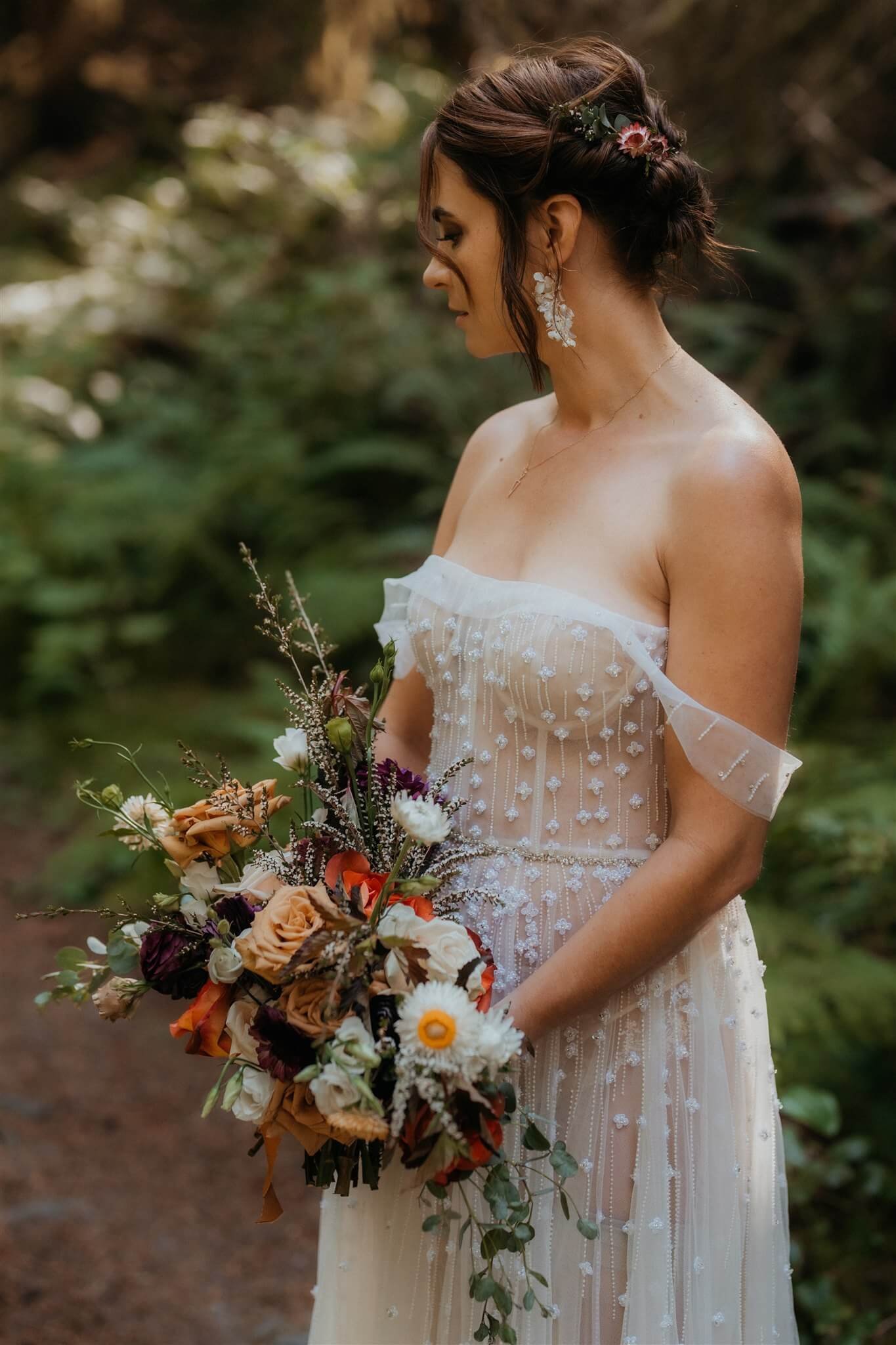 Bride with white sleeveless wedding dress holding colorful floral bouquet