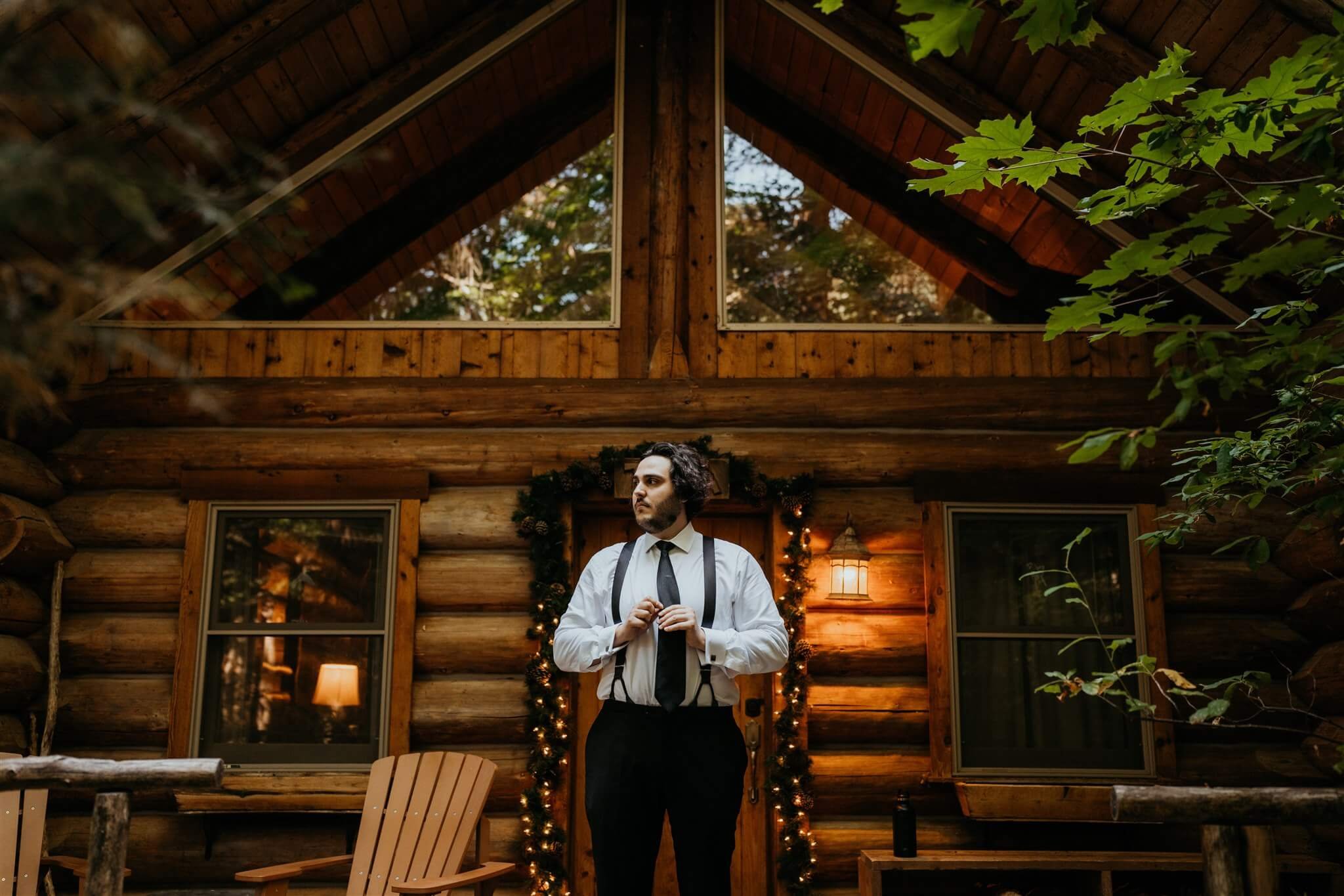 Groom getting ready in front of wood cabin at Wellspring Spa