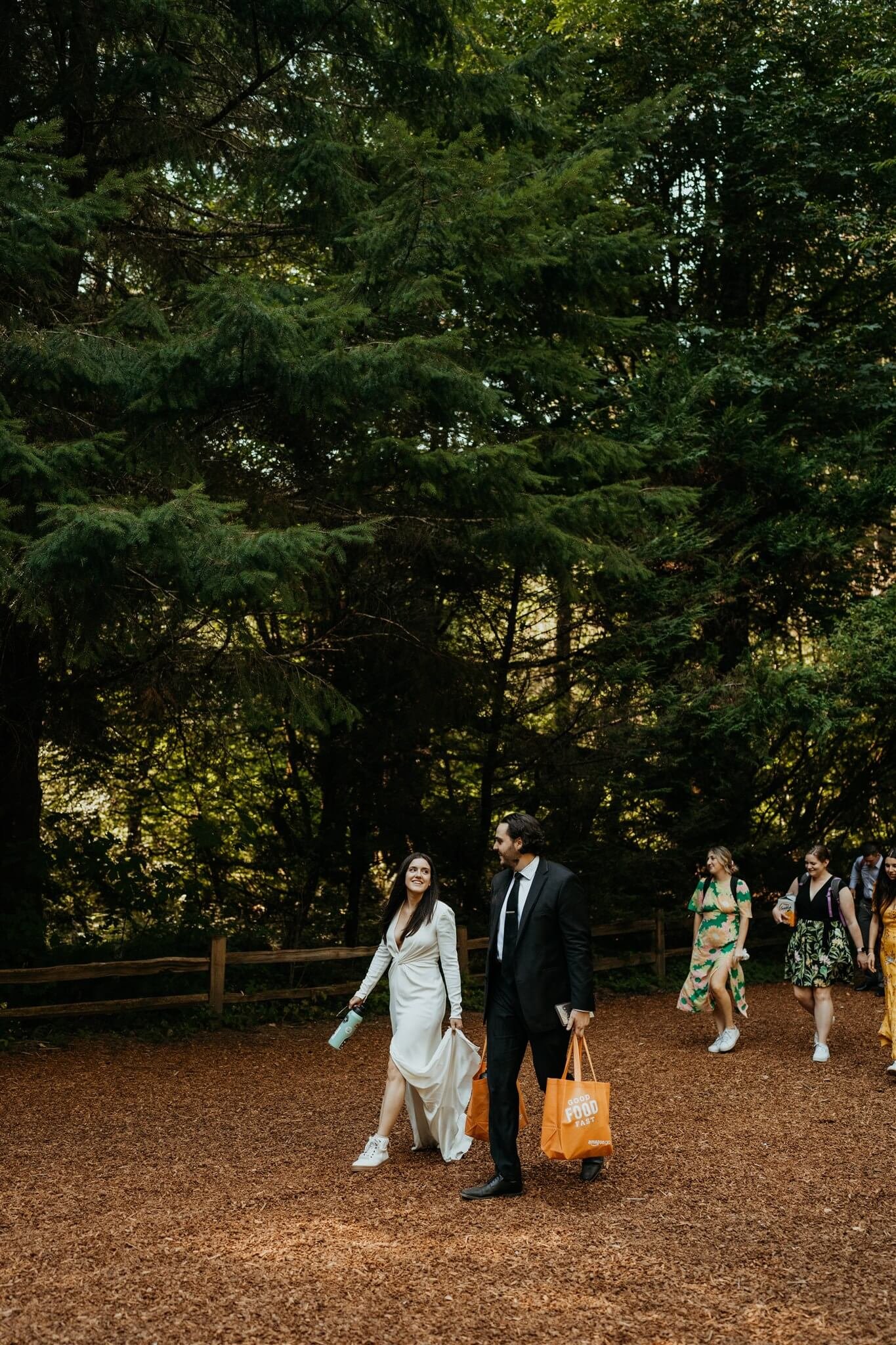 Bride and groom walking through the forest with their friends at their adventure wedding