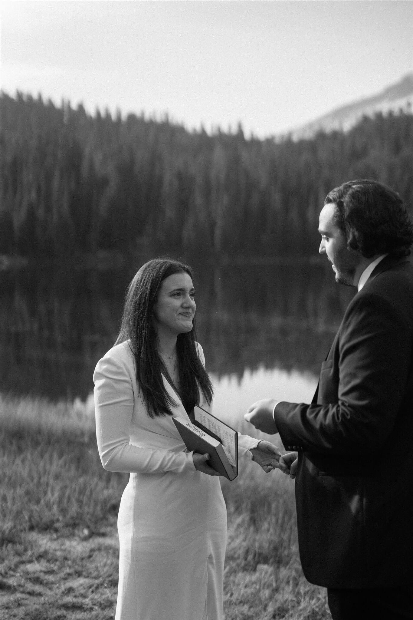 Bride and groom smile while reading vows at their intimate adventure wedding with friends