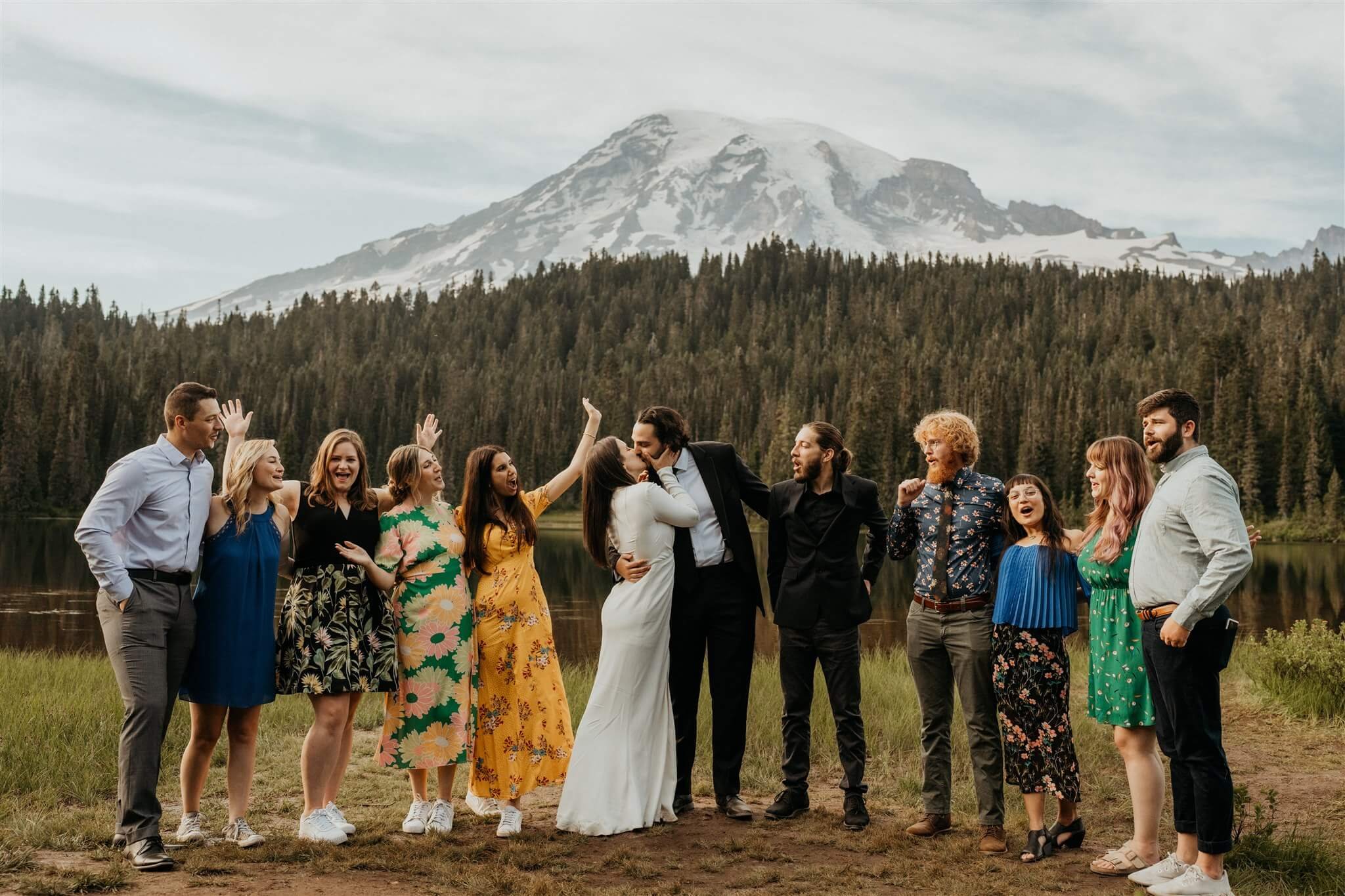 Bride and groom kiss while friends cheer at Mt Rainier elopement