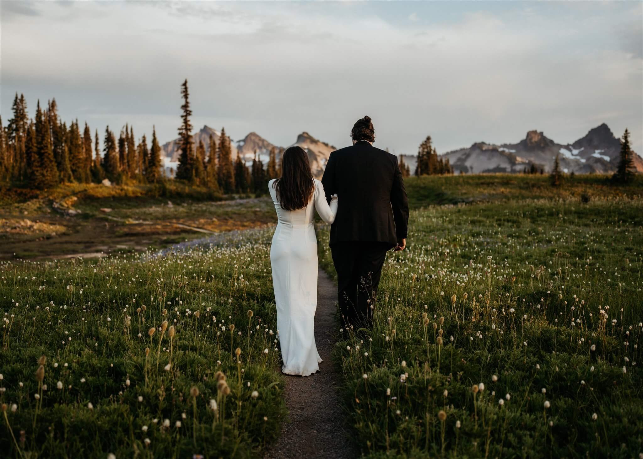 Bride and groom walking arm in arm through the field at their Mount Rainier adventure wedding