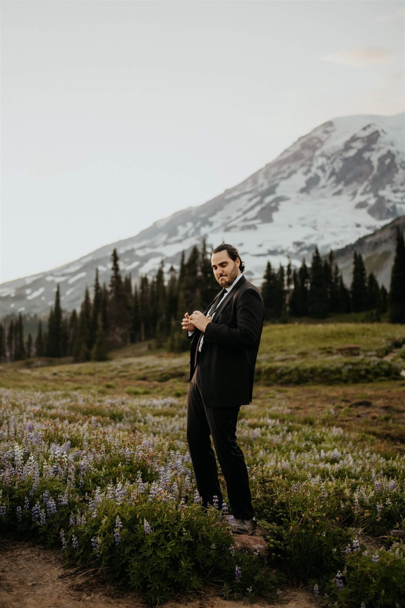 Groom in black suit acting silly during Mt Rainier elopement portraits