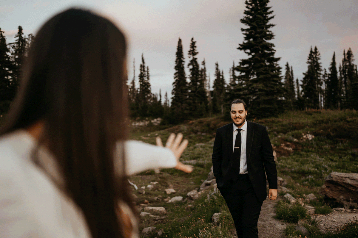 Groom walking towards bride during sunset elopement photo session at Mount Rainier