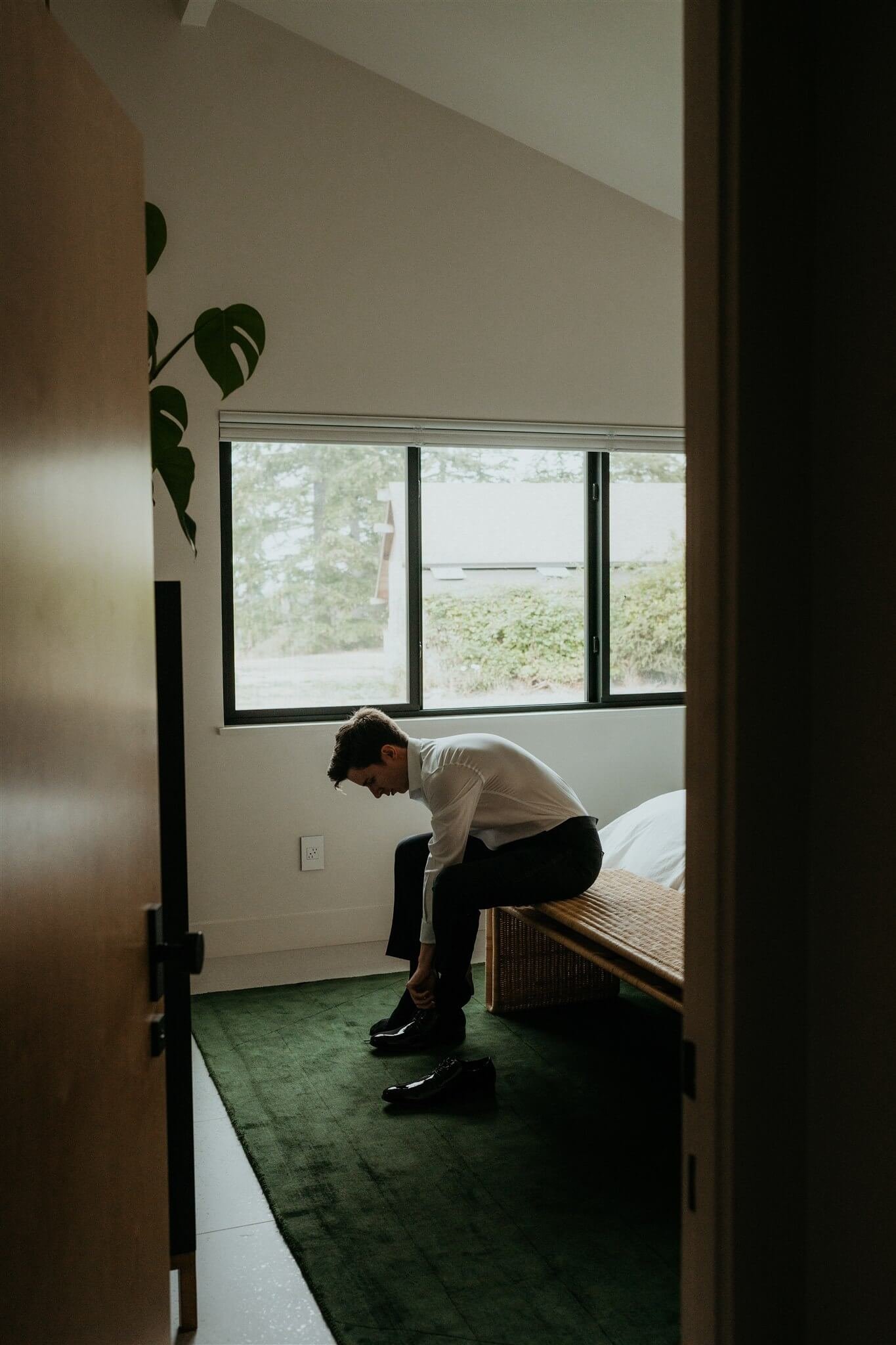 Groom sitting on the edge of the bed tying his shoes before foggy Artist Point elopement