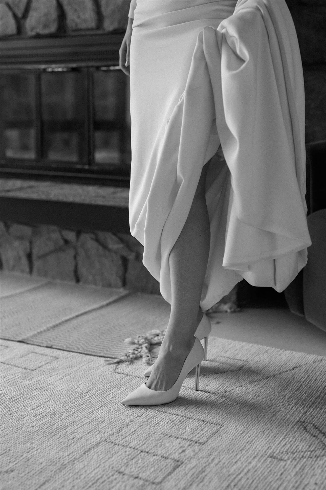 Bride putting on classy white wedding heels before elopement at Artist Point