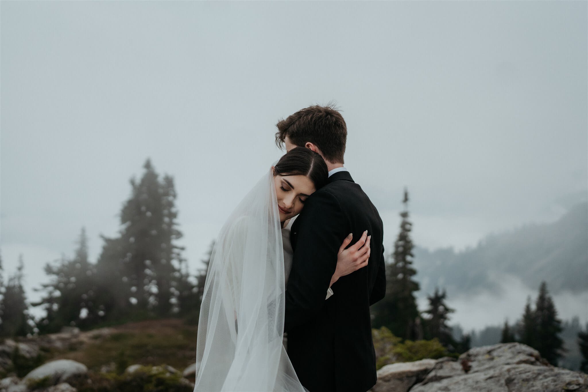 Bride and groom hug during couple photos at foggy Artist Point elopement