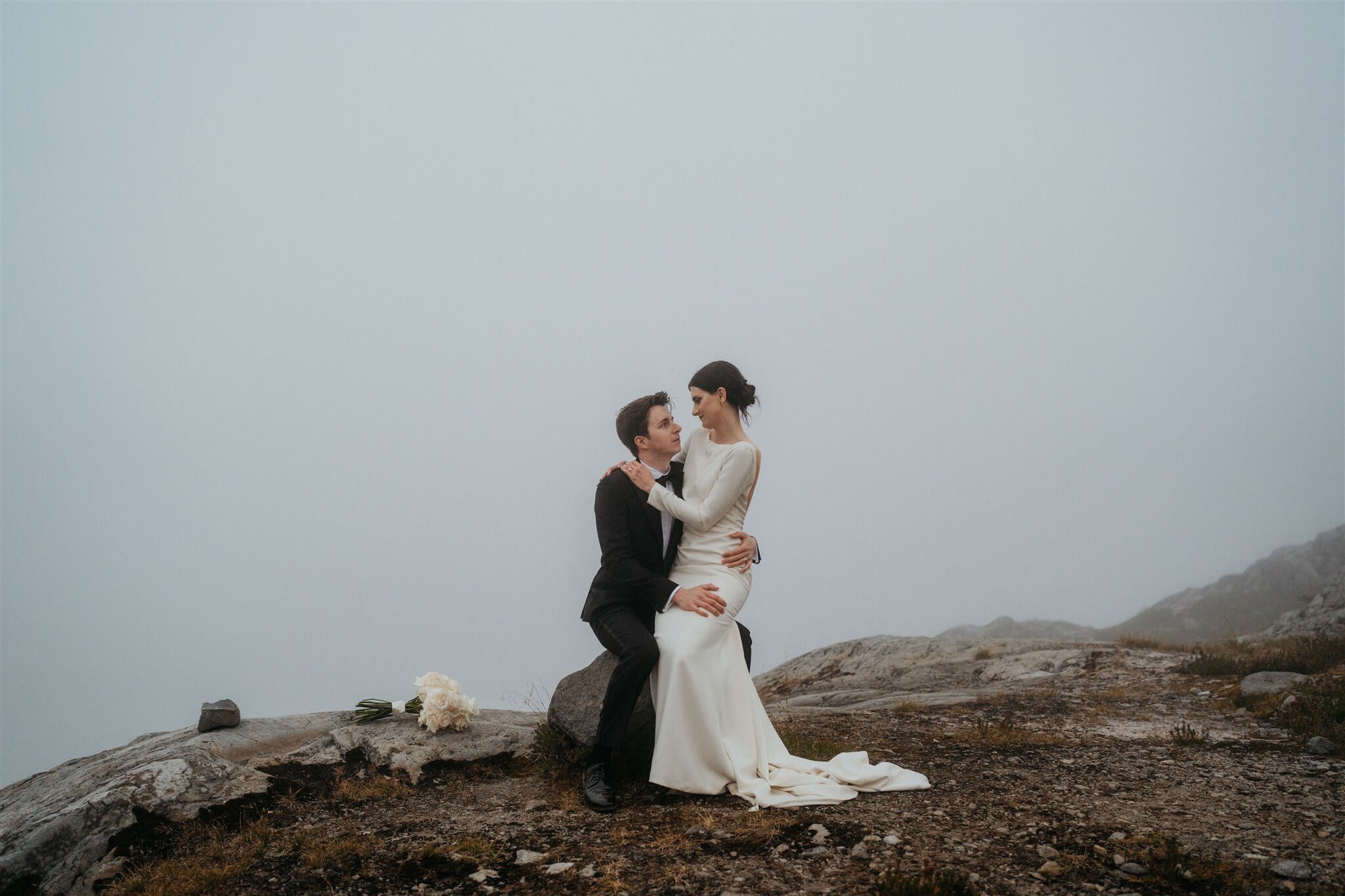 Bride sitting on groom's lap during foggy Artist Point elopement adventure photos