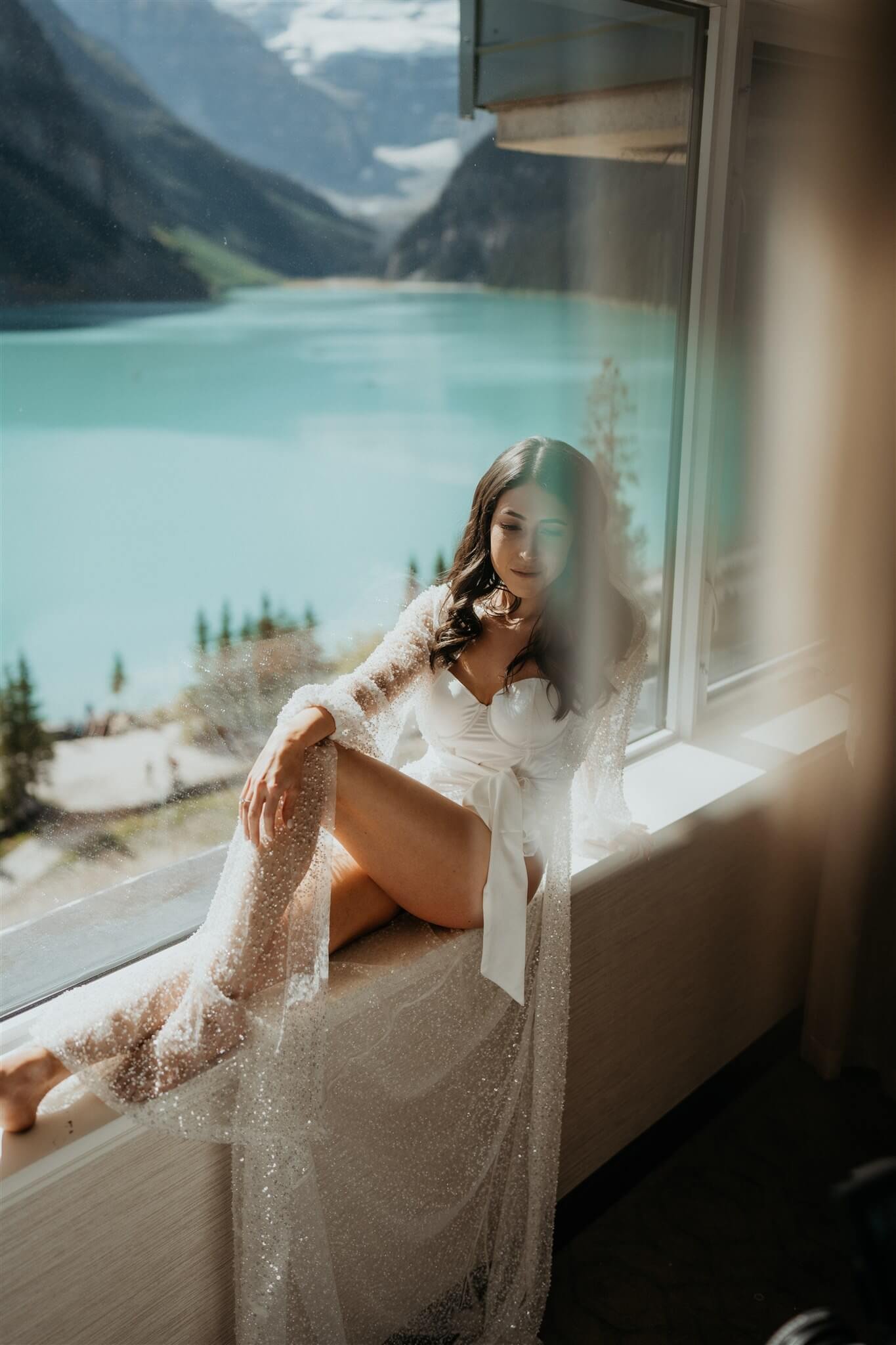 Bride wearing sheer sparkly robe while getting ready for Lake Louise wedding in Alberta, Canada