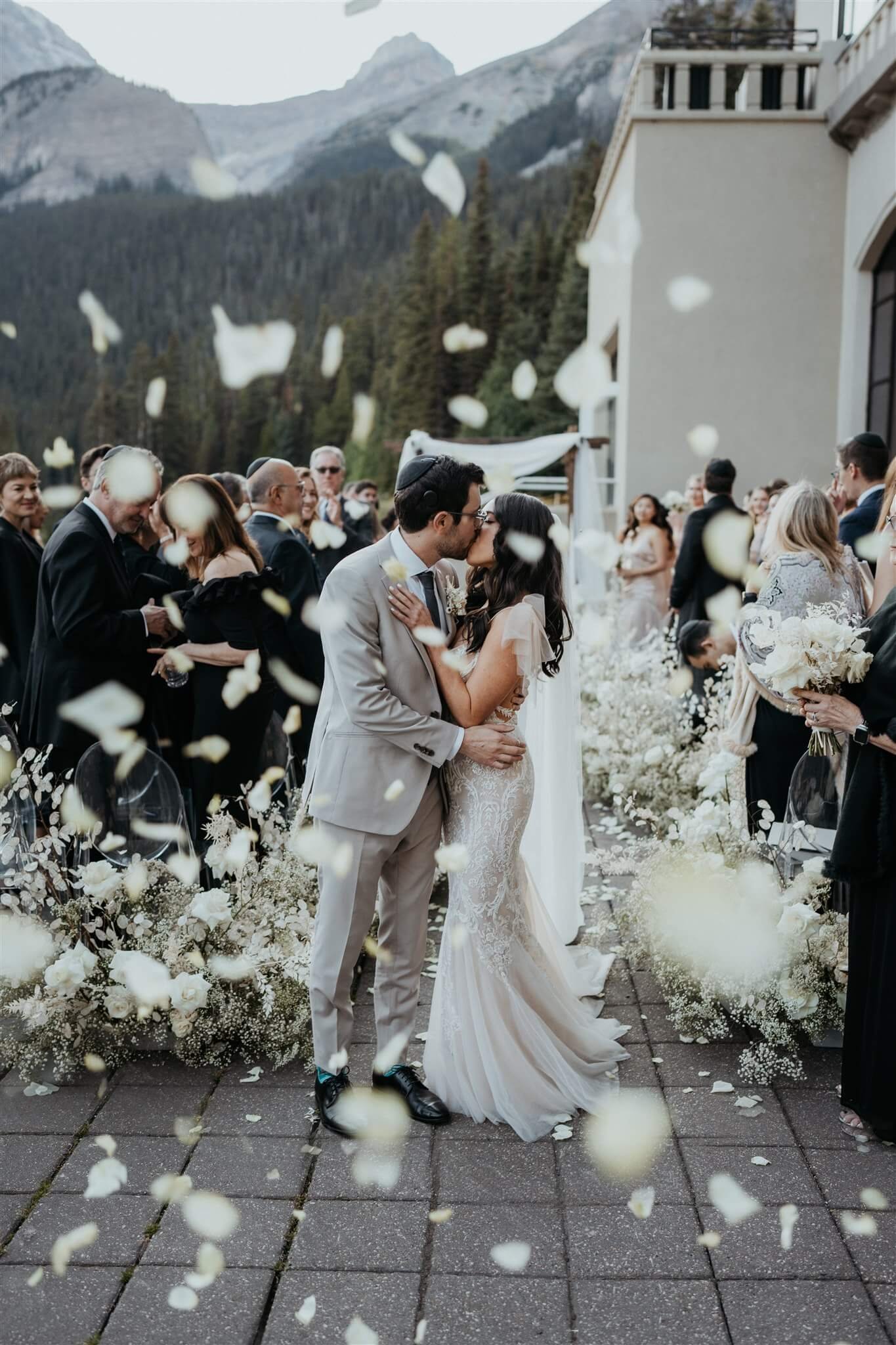 Bride and groom kiss after outdoor wedding ceremony by Lake Louise