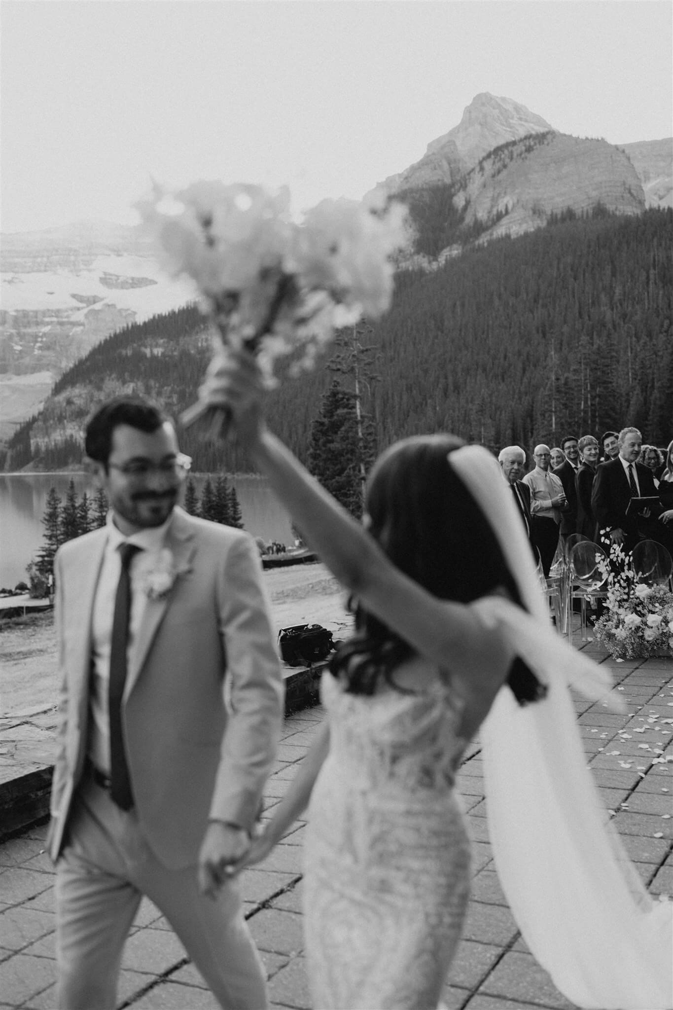 Bride and groom cheer as they exit the aisle at their Lake Louise wedding
