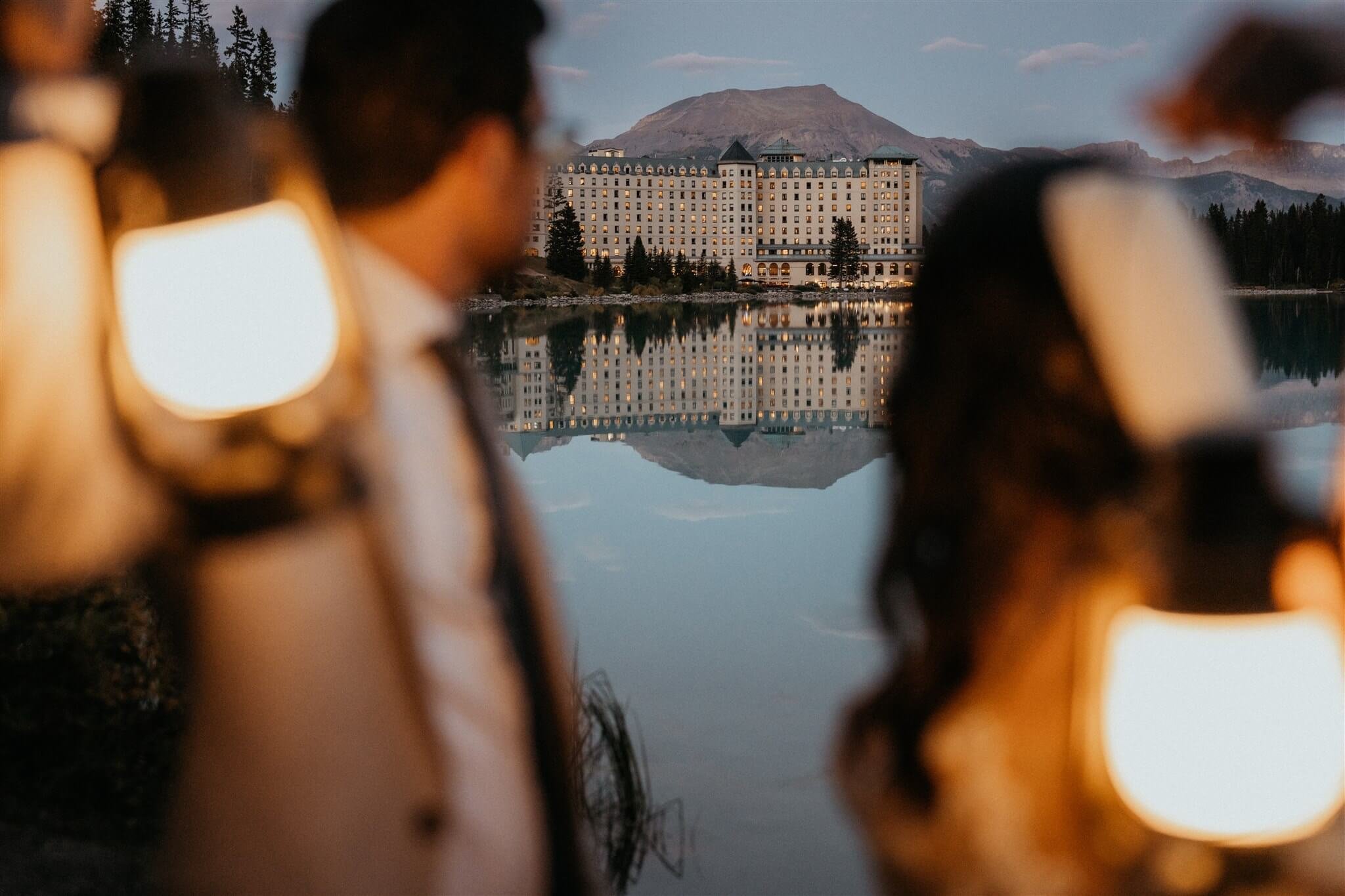 Bride and groom holding lanterns by Lake Louise at their luxury wedding at Fairmont Chateau Lake Louise hotel