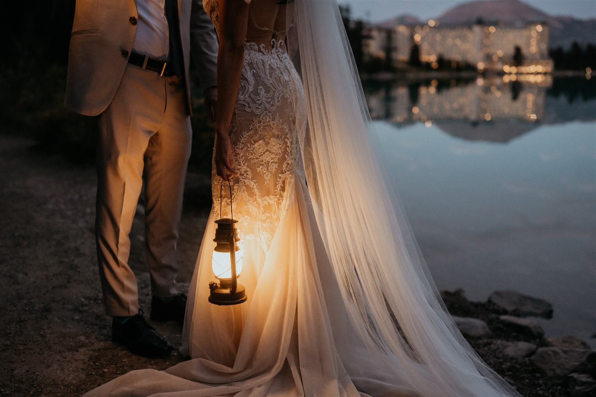 Bride and groom holding lanterns by Lake Louise at their luxury wedding at Fairmont Chateau Lake Louise hotel